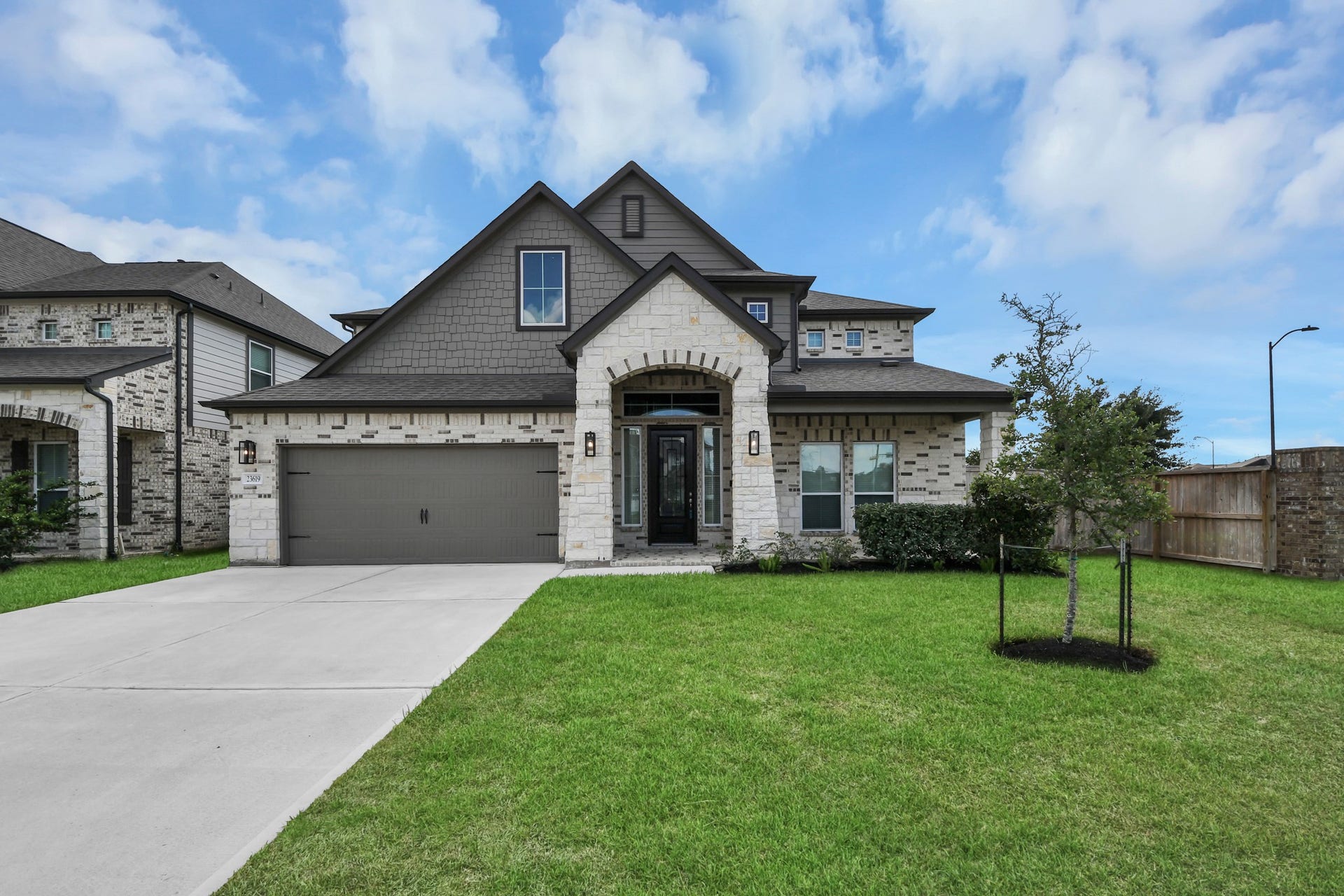 23619 Iris Field Court, Katy, TX 77493 Impressive curb appeal with a striking stone-and-brick exterior, modern architectural details, lush landscaping, and an inviting covered entry.