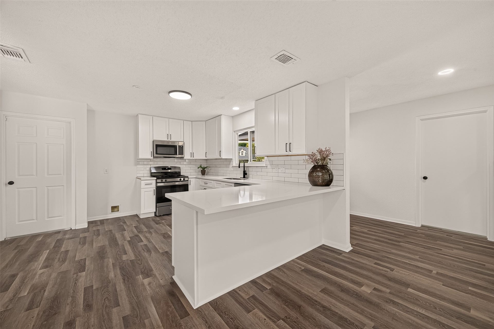 12747 Ashford Knoll Drive, Houston, TX 77082 Sleek and modern kitchen featuring crisp white cabinetry, stainless steel appliances, and a spacious peninsula with elegant countertops