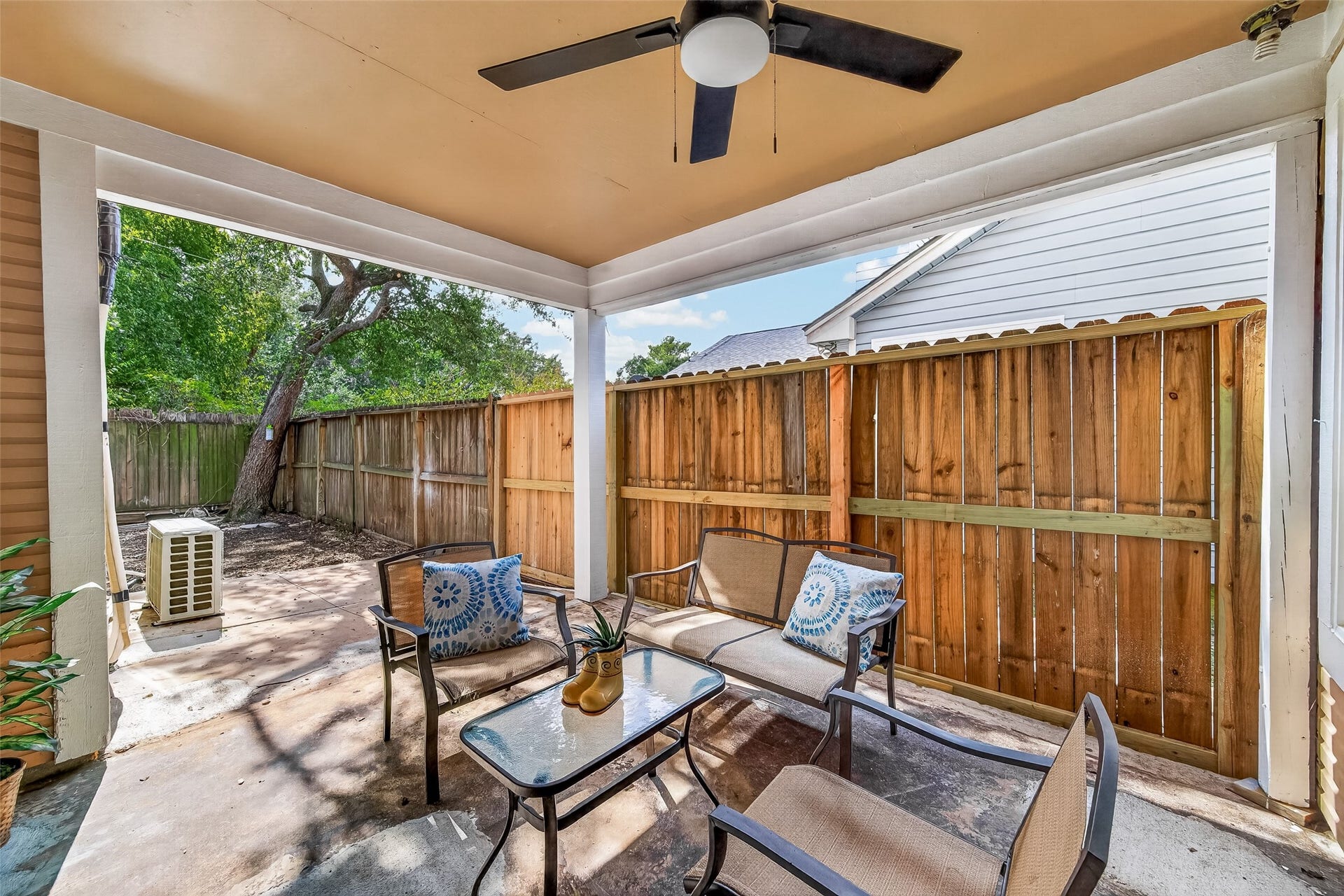 12747 Ashford Knoll Drive, Houston, TX 77082 Charming, covered patio with cozy seating and ceiling fan, perfect for relaxing or entertaining.