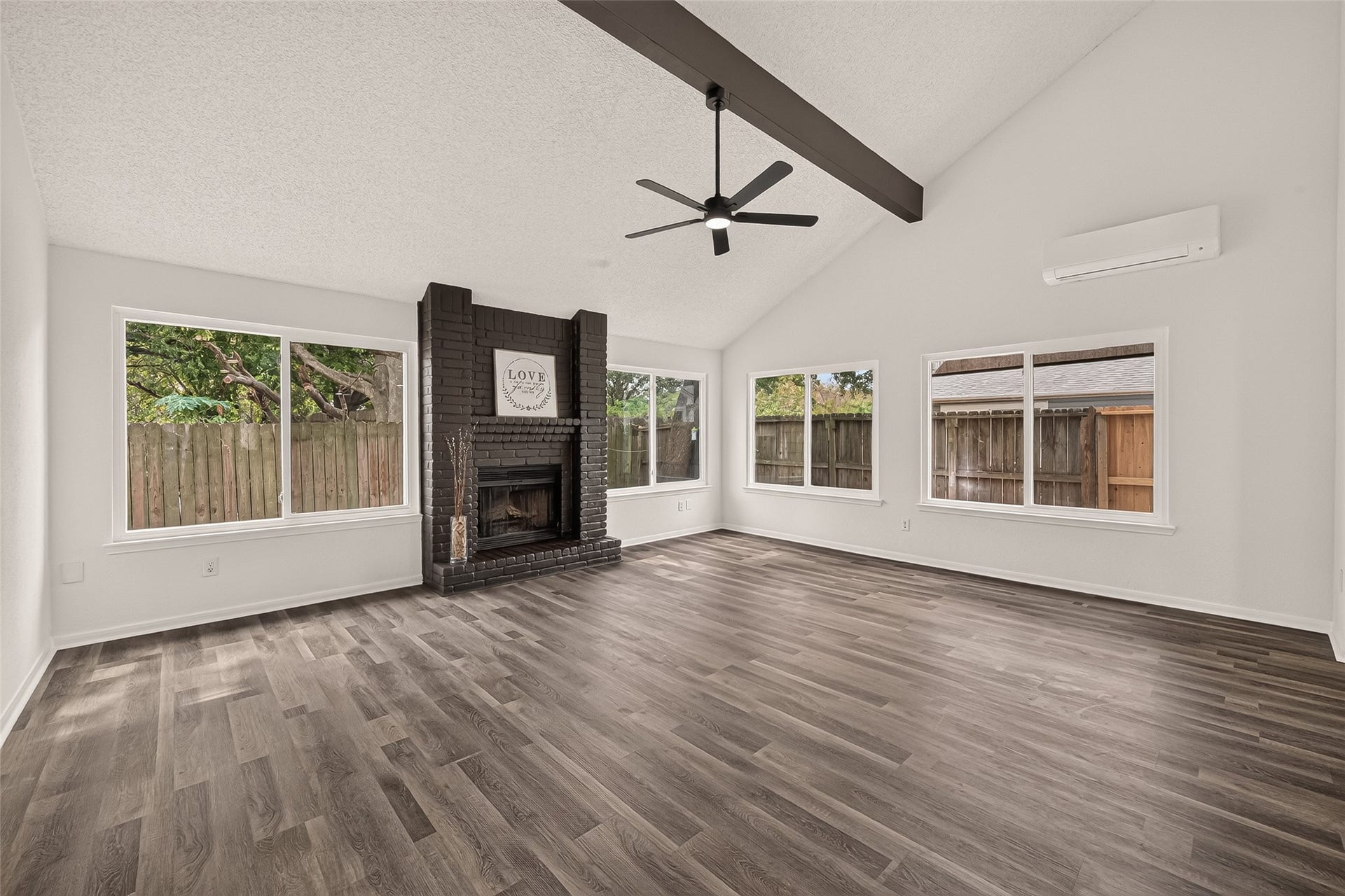 12747 Ashford Knoll Drive, Houston, TX 77082 Spacious living room with vaulted ceilings, featuring a sleek dark brown brick fireplace, and abundant natural light from large windows.