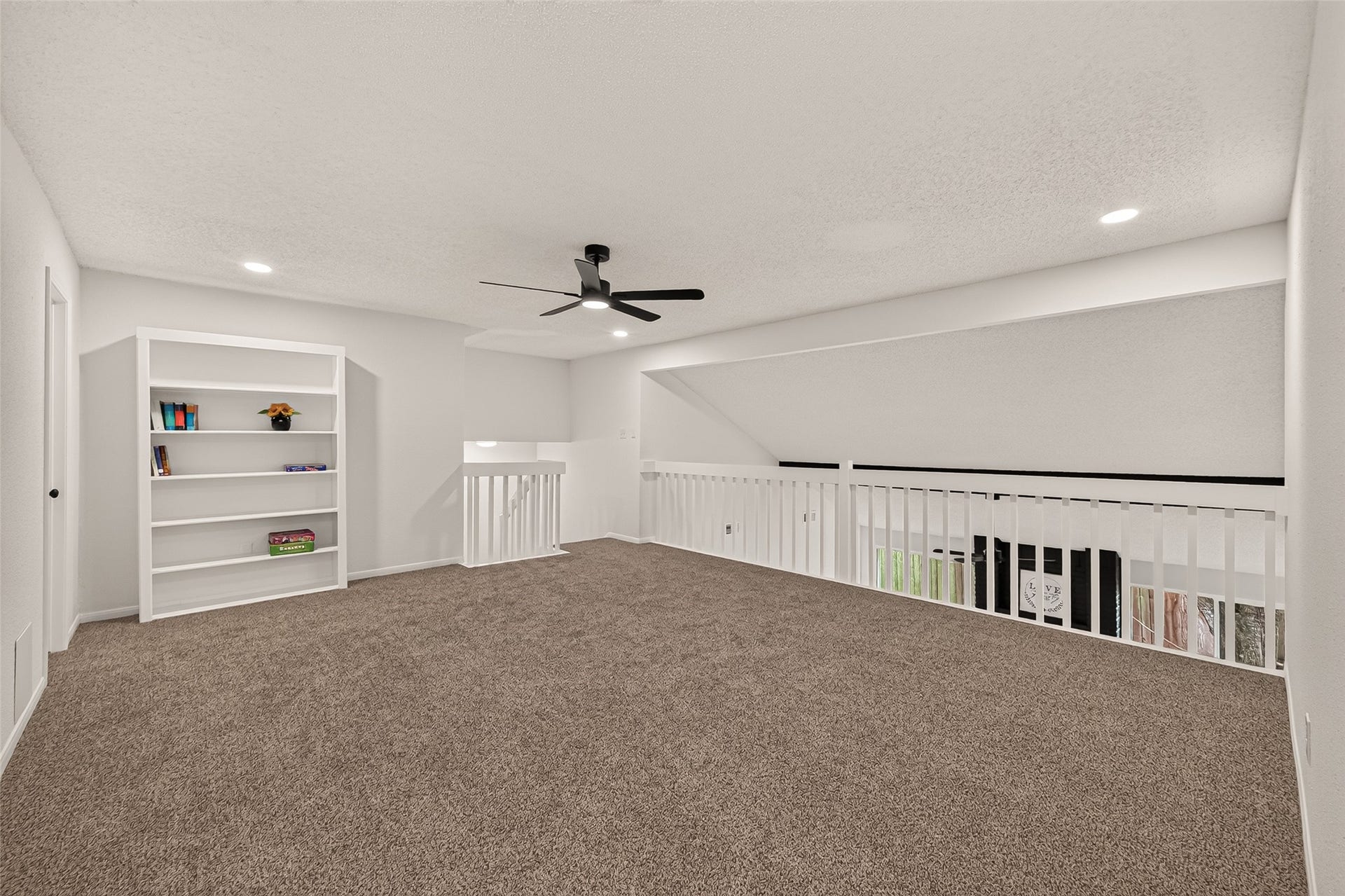 12747 Ashford Knoll Drive, Houston, TX 77082 Spacious game-room with plush new carpeting, built-in shelving, and a modern ceiling fan, ideal for a cozy living space or home office.