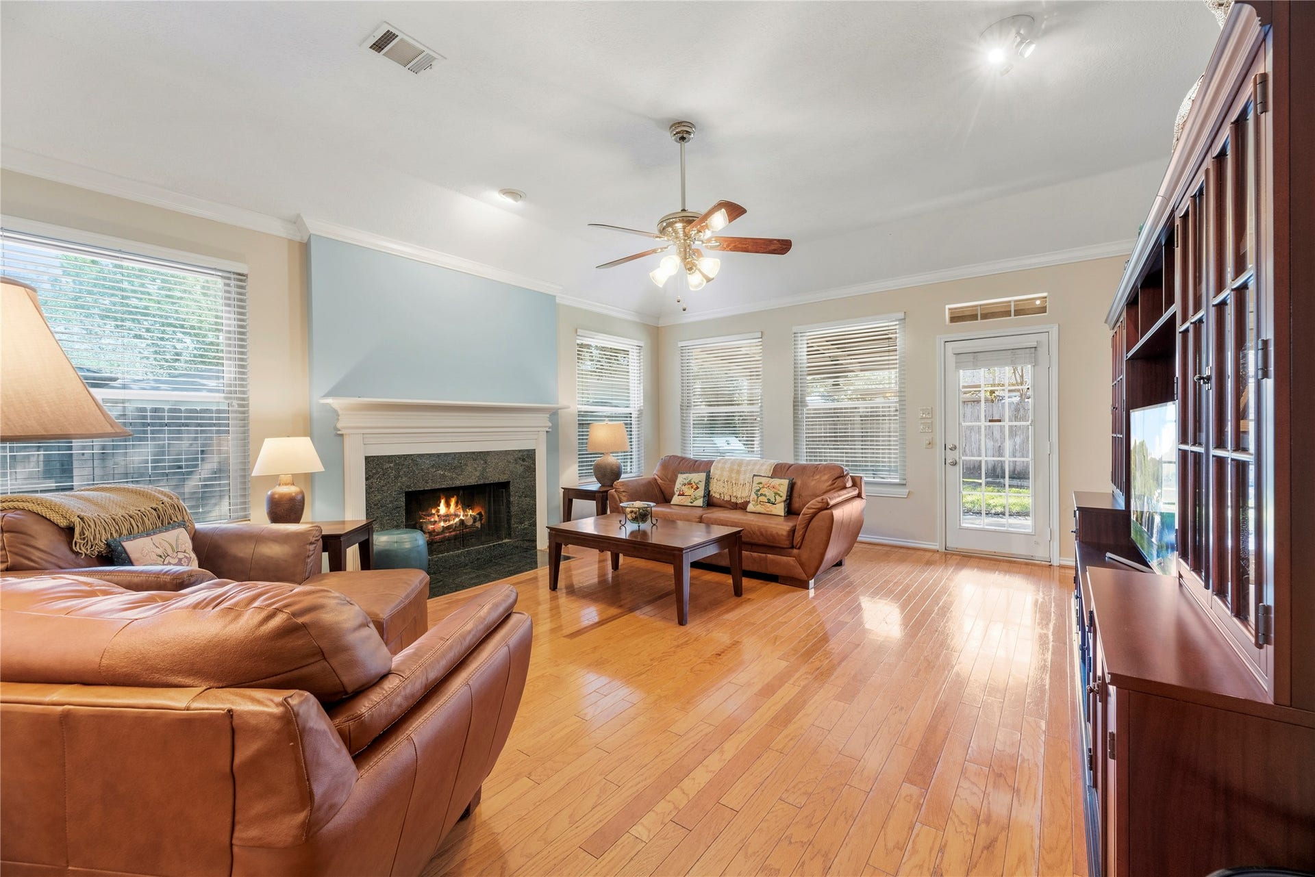 Cozy living room with a warm fireplace, elegant hardwood floors, and abundant natural light from large windows, perfect for relaxation and entertaining.