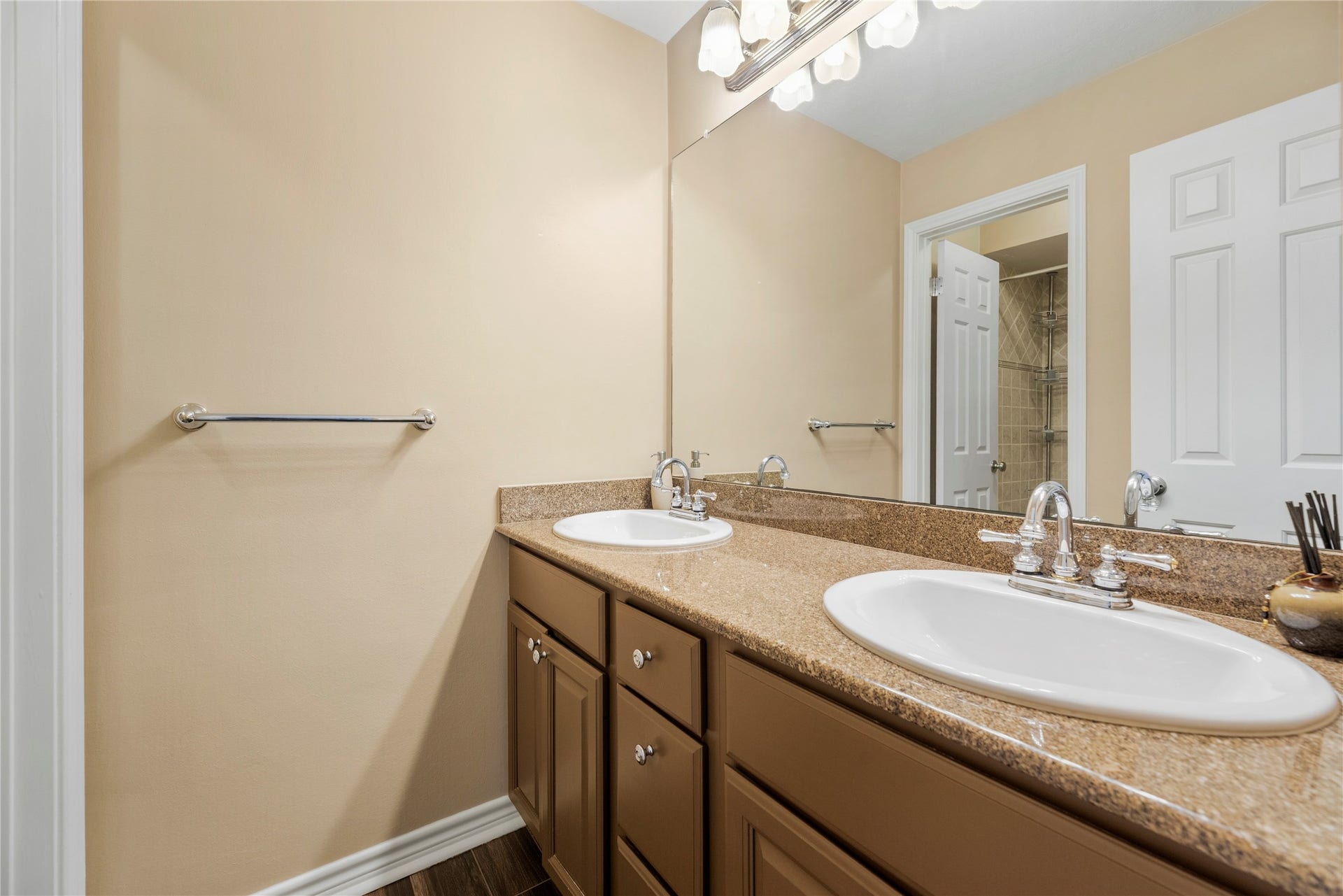 Secondary bathroom with dual sinks, granite countertops, and ample cabinet space. Sink area is separate from shower and toilet.