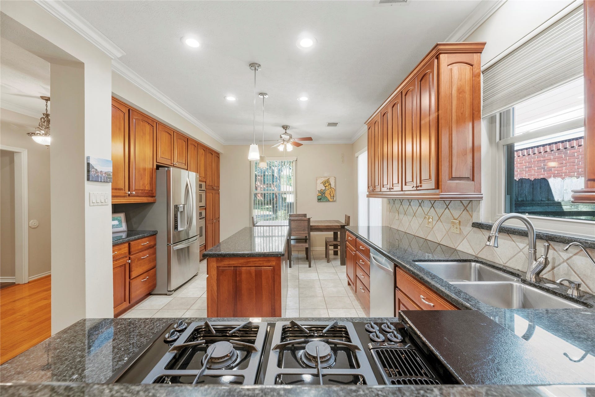 Spacious island kitchen with rich wood cabinetry, granite countertops, and stainless steel appliances .