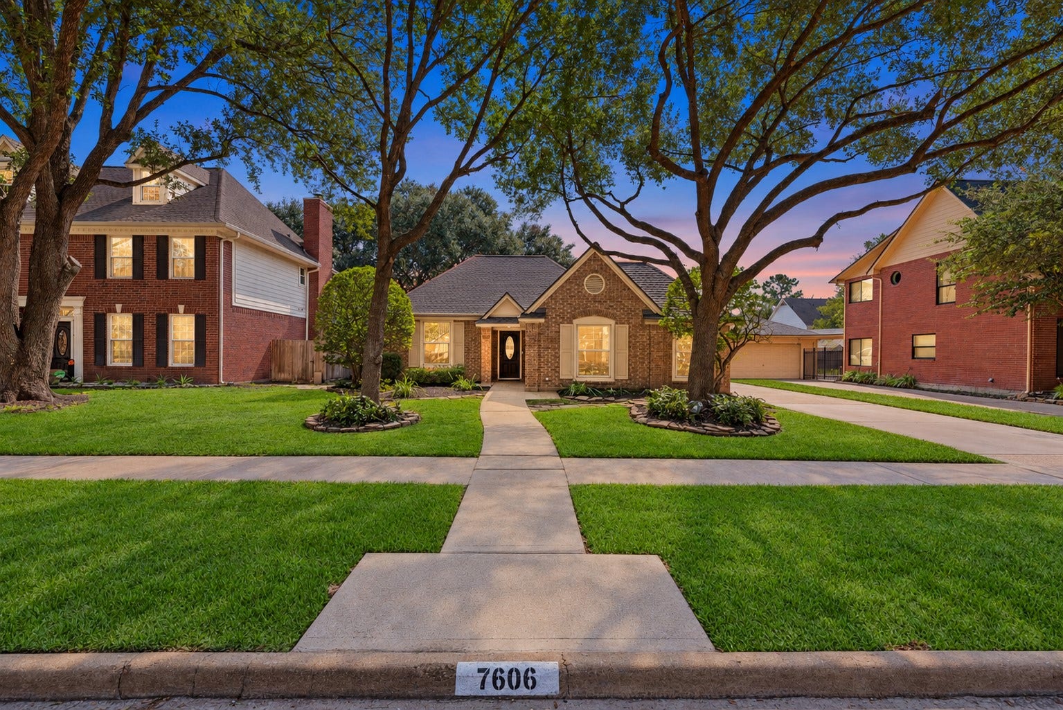 Charming single-story brick home with elegant landscaping and mature trees.