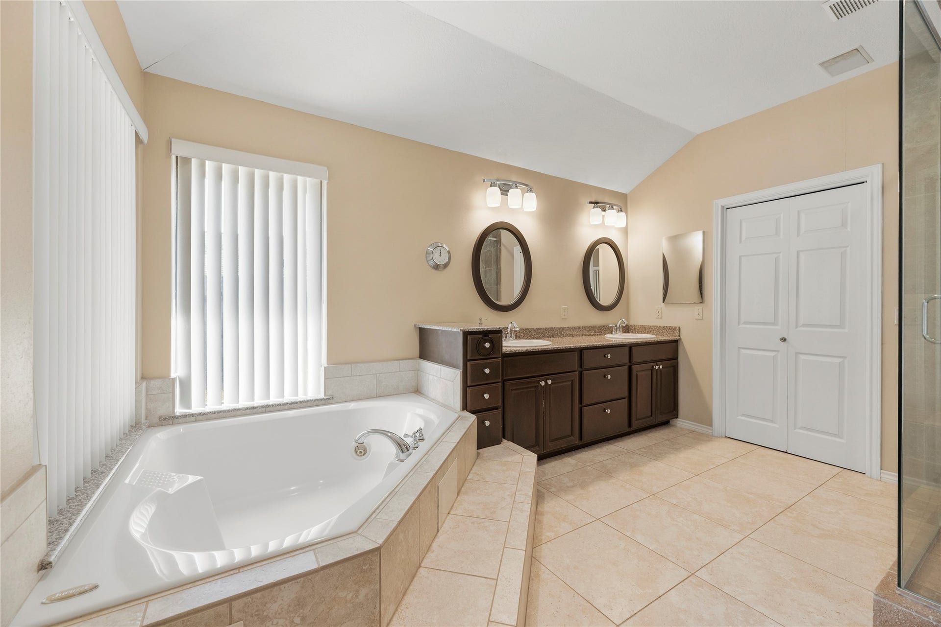 A great sized primary bathroom featuring a luxurious soaking tub, dual vanity with elegant fixtures, and ample natural light.