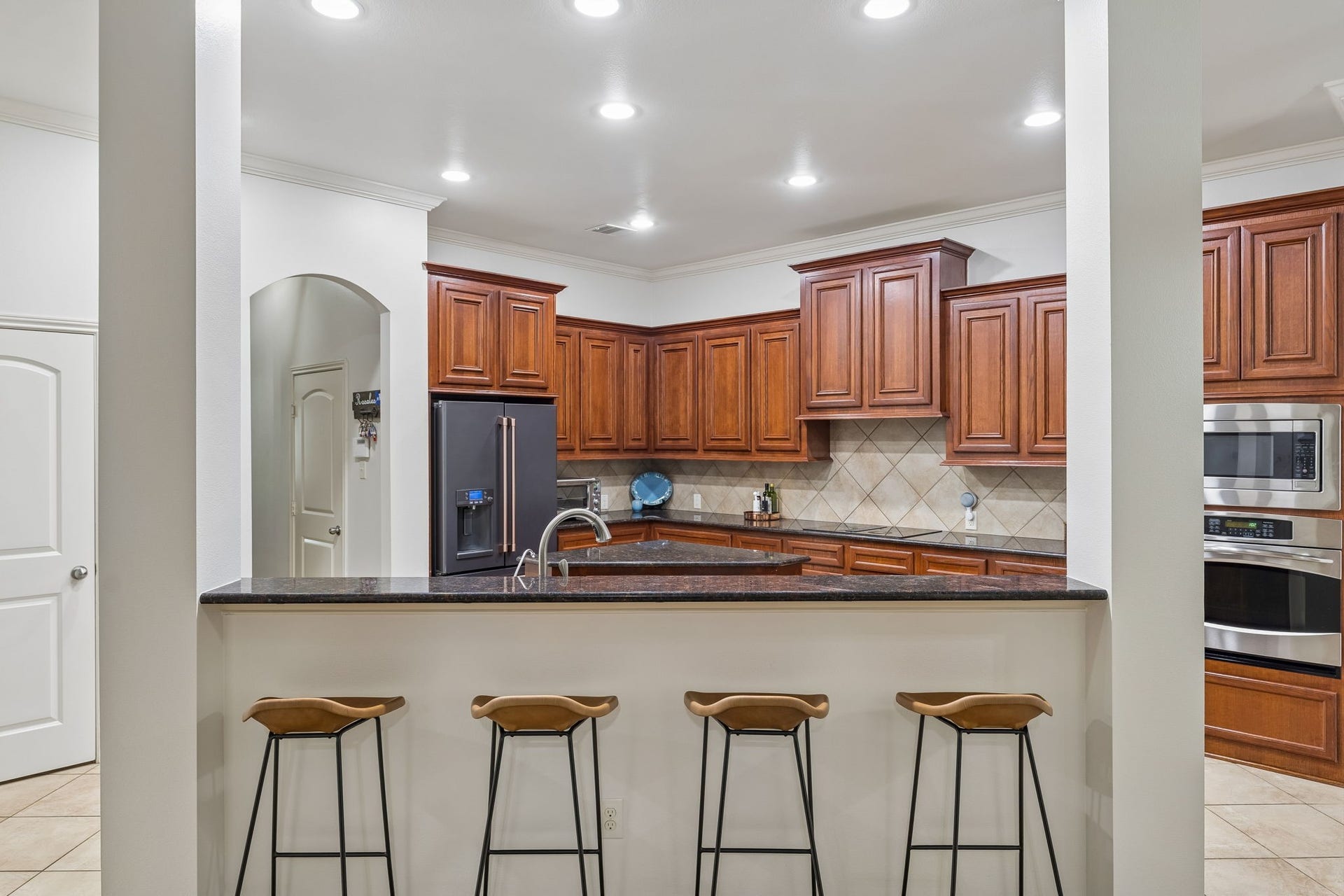 2927 Auburn Creek Lane, League City, TX 77573 Spacious kitchen with rich wood cabinetry, granite countertops, stainless steel appliances, and breakfast bar seating.