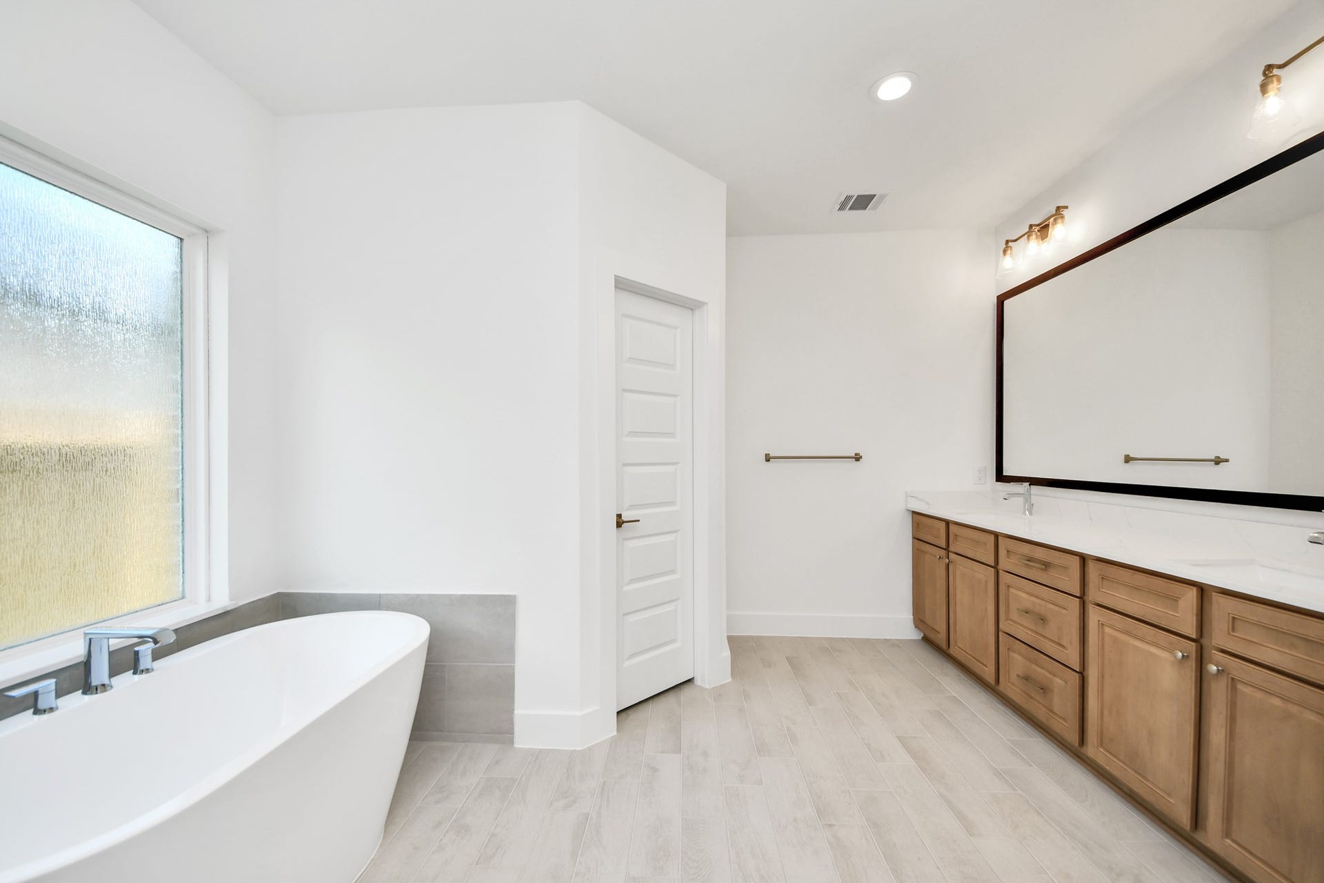 3217 Skerne Spring Drive, Spring, TX 77373 Escape to a spa-like oasis in this primary bathroom. Enjoy a walk-in shower with tile surround, a separate garden tub with custom detailing, and an elegant vanity featuring light countertops, modern hardware, and beautiful vanity lights. Experience luxury and relaxation in every detail. Sample photo of completed home with similar floor plan. Actual colors and selections may vary.
