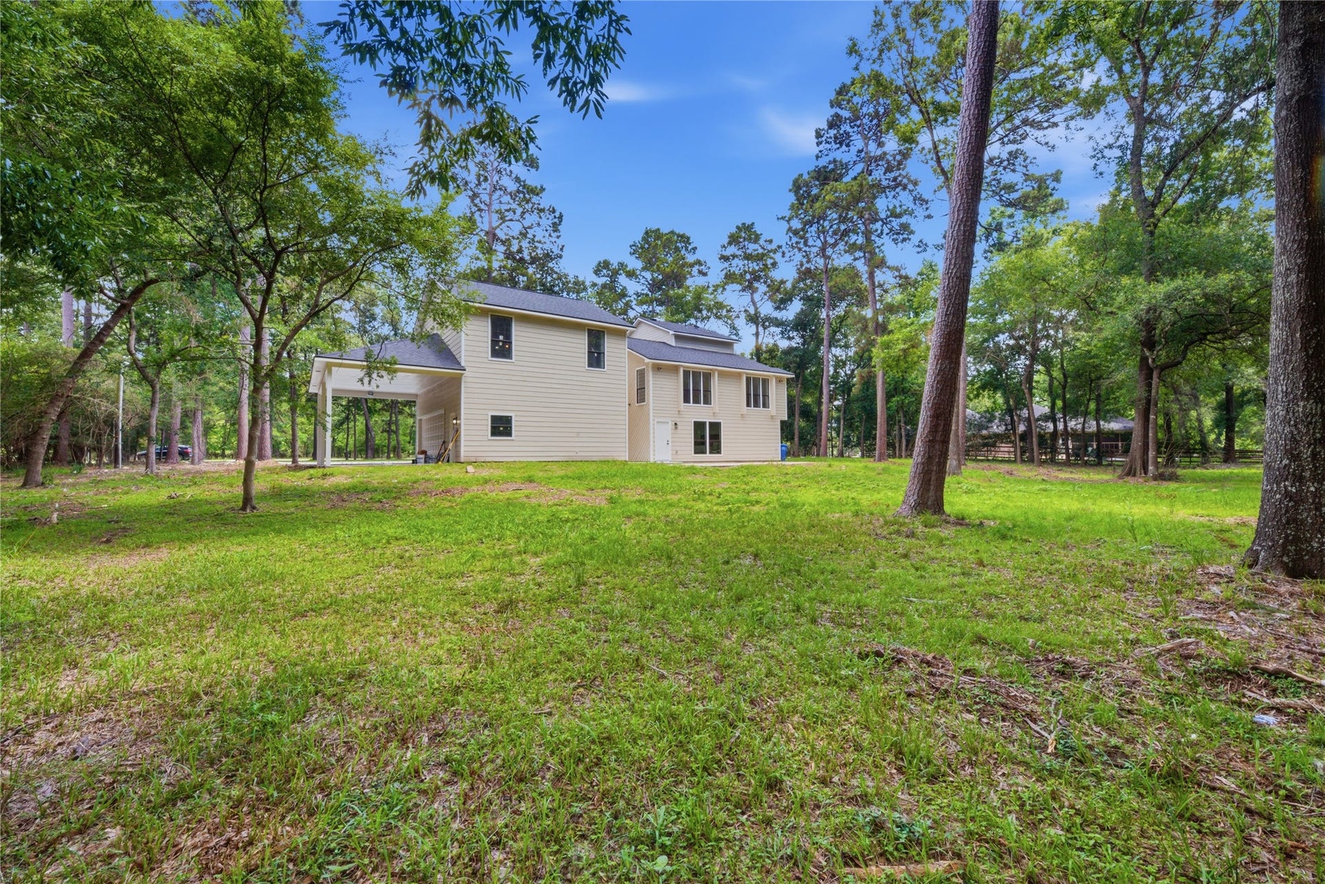 40203 Cimarron Way, Magnolia, TX 77354 Side view showing the relationship between the main home and detached garage structure, both nestled within the mature treeline. Generous side yard ideal for entertaining, gardening, or equestrian use.