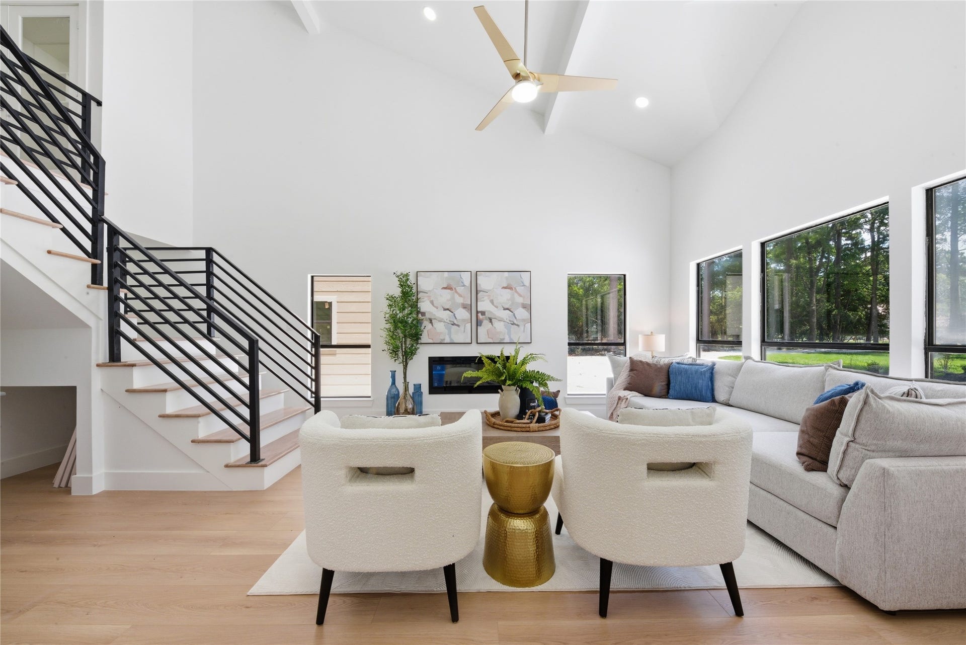 40203 Cimarron Way, Magnolia, TX 77354 Soaring 20-ft ceilings, floating steel staircase with white oak treads and horizontal black metal rail, linear electric fireplace, and walls of windows overlooking the wooded acreage. Wide- luxury vinyl plank floors throughout.