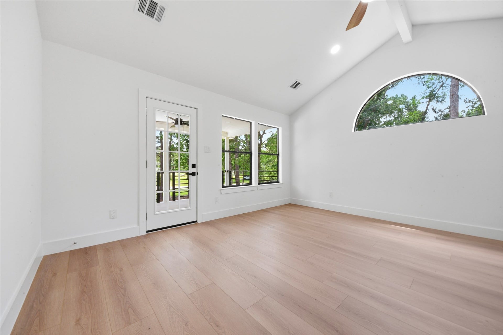 40203 Cimarron Way, Magnolia, TX 77354 Stunning third-floor second primary suite featuring vaulted ceiling with exposed beam, designer ceiling fan, half-moon accent window, and private door access to a covered balcony overlooking the treeline.