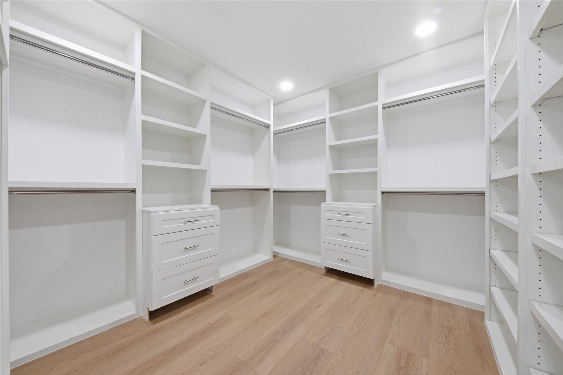 40203 Cimarron Way, Magnolia, TX 77354 Boutique-style primary walk-in closet featuring built-in shaker drawers, double hanging rods, adjustable shelving, custom shoe wall, and wide-plank floors. Designed for serious storage and daily luxury.