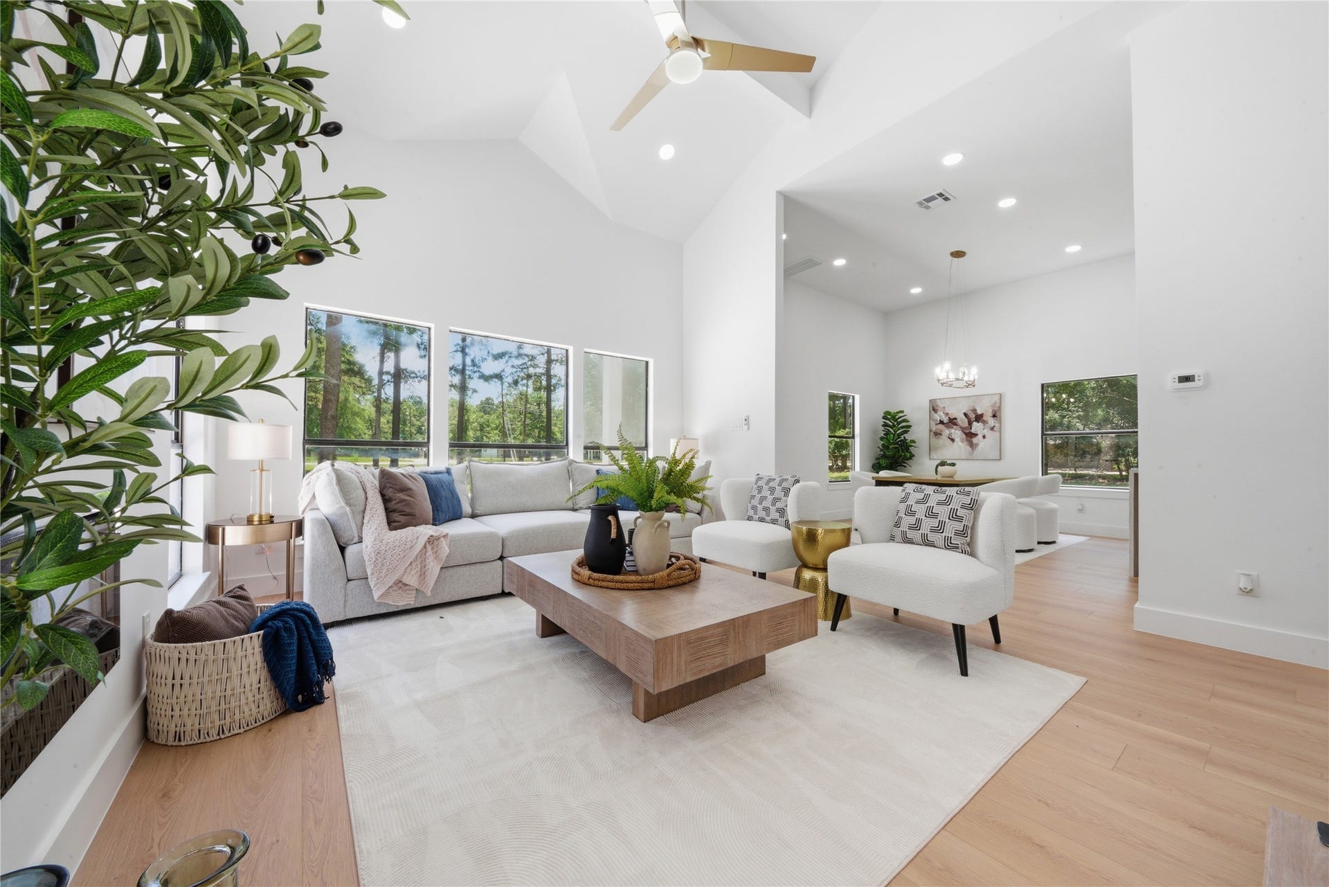 40203 Cimarron Way, Magnolia, TX 77354 Open-concept flow from living room to dining area and kitchen beyond. Statement chandelier visible in dining nook, soaring vaulted ceilings, and seamless sight lines make this layout perfect for entertaining.