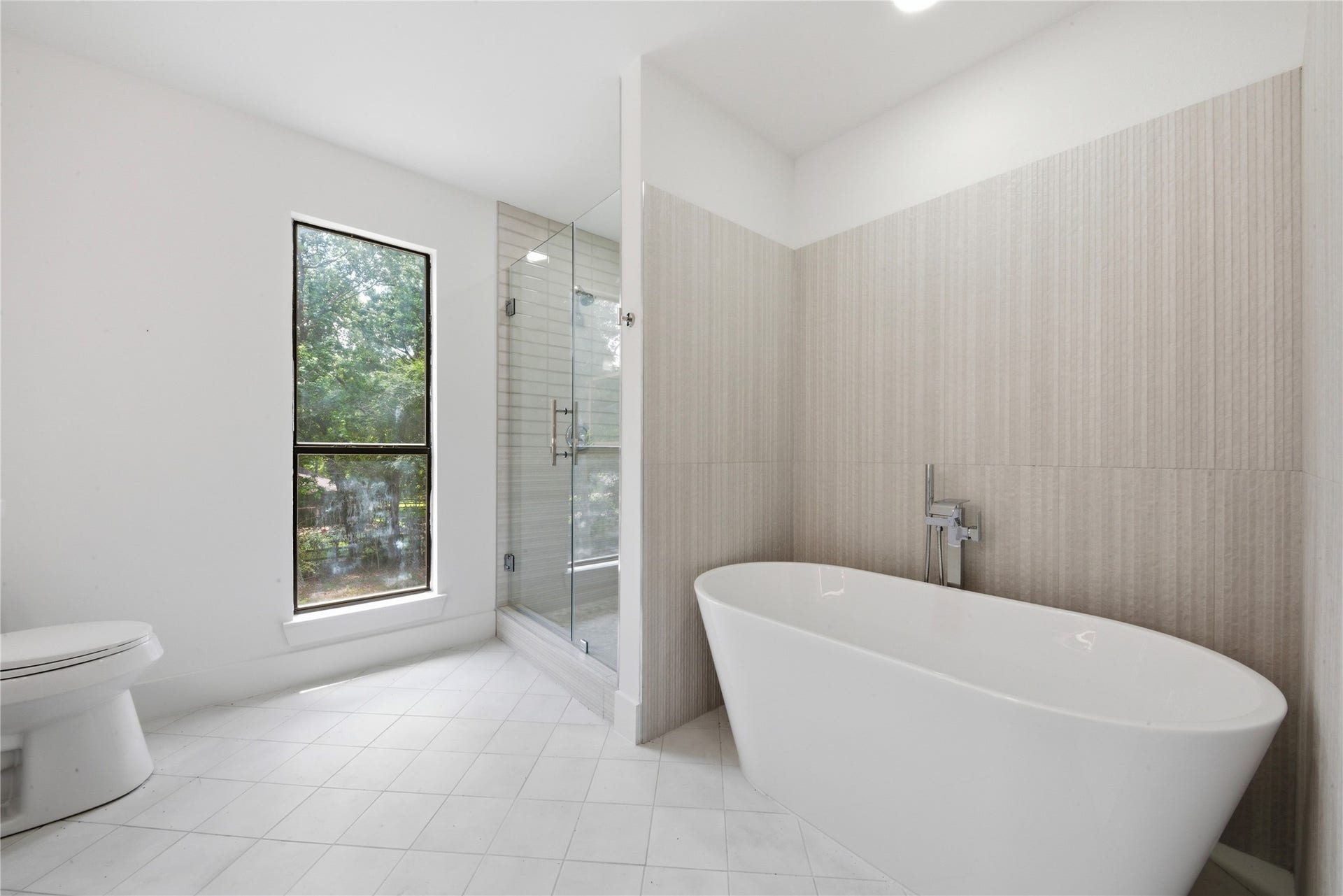 40203 Cimarron Way, Magnolia, TX 77354 Spa-style retreat featuring a deep freestanding soaking tub, hand-held tub filler, and oversized frameless glass shower with floor-to-ceiling vertical tile. A true sanctuary for the second primary suite.