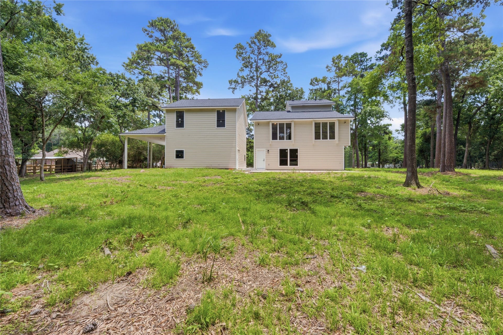 40203 Cimarron Way, Magnolia, TX 77354 Daytime view of the rear elevation showcasing the home's substantial profile, modern board-and-batten siding, and the scale of the surrounding wooded lot. AC units neatly tucked at the side.
