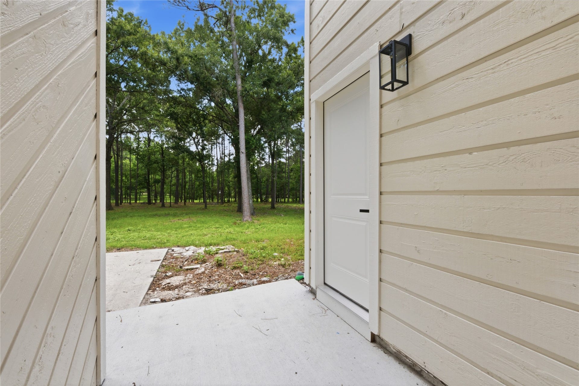 40203 Cimarron Way, Magnolia, TX 77354 Private side entrance to the detached structure with designer black exterior sconce, board-and-batten siding, and walk-out access to the 1.67-acre wooded lot.