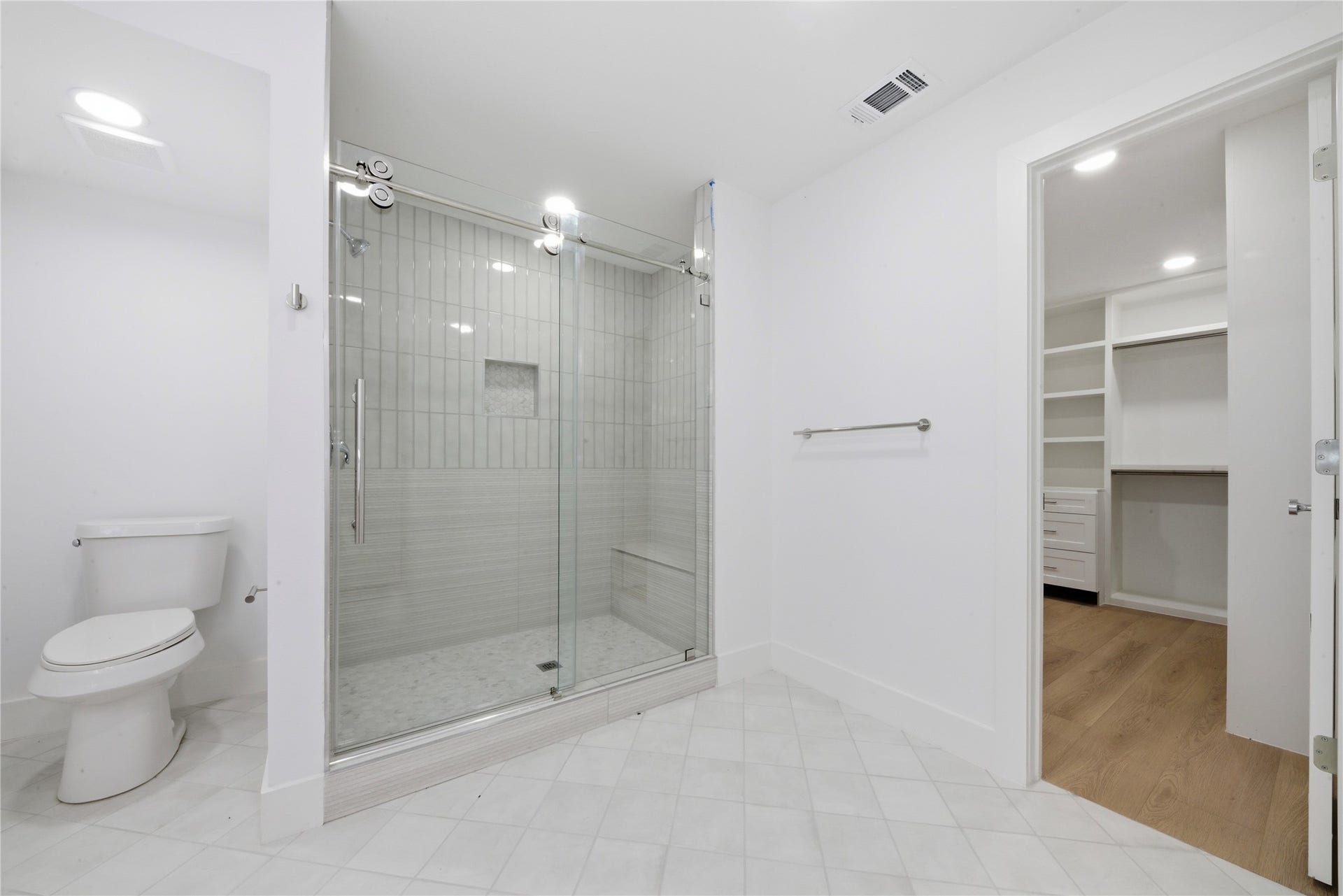 40203 Cimarron Way, Magnolia, TX 77354 Oversized frameless glass walk-in shower with vertical tile, built-in bench, and shampoo niche. Doorway opens directly to the custom-built walk-in closet, a true ensuite layout.