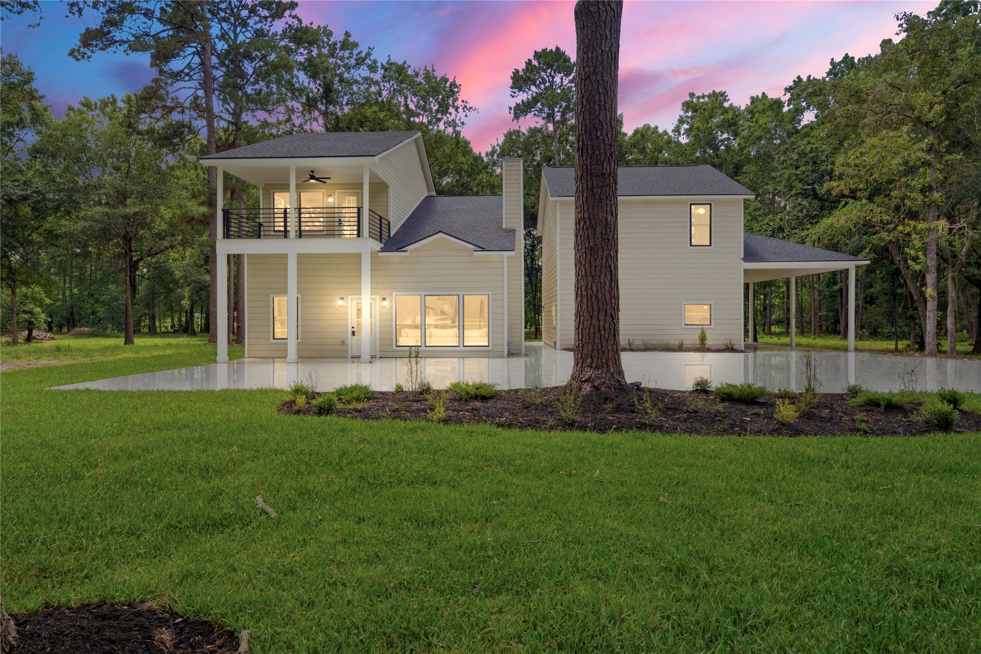 40203 Cimarron Way, Magnolia, TX 77354 Stunning twilight view of this 3,243 SF modern farmhouse on 1.67 wooded acres in Cimarron Country. Two-story design with covered upper balcony, board-and-batten siding, and detached 3-car garage with room to the right.