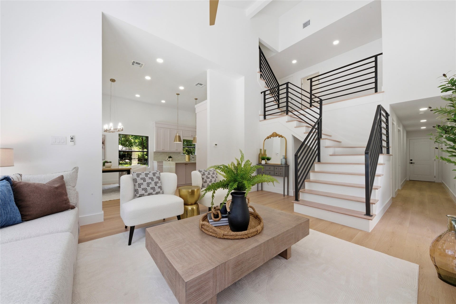 40203 Cimarron Way, Magnolia, TX 77354 Dramatic entry showcasing the architectural floating steel staircase, soaring ceilings, and views into the kitchen and dining area. White oak treads and horizontal black metal rail create a contemporary statement.