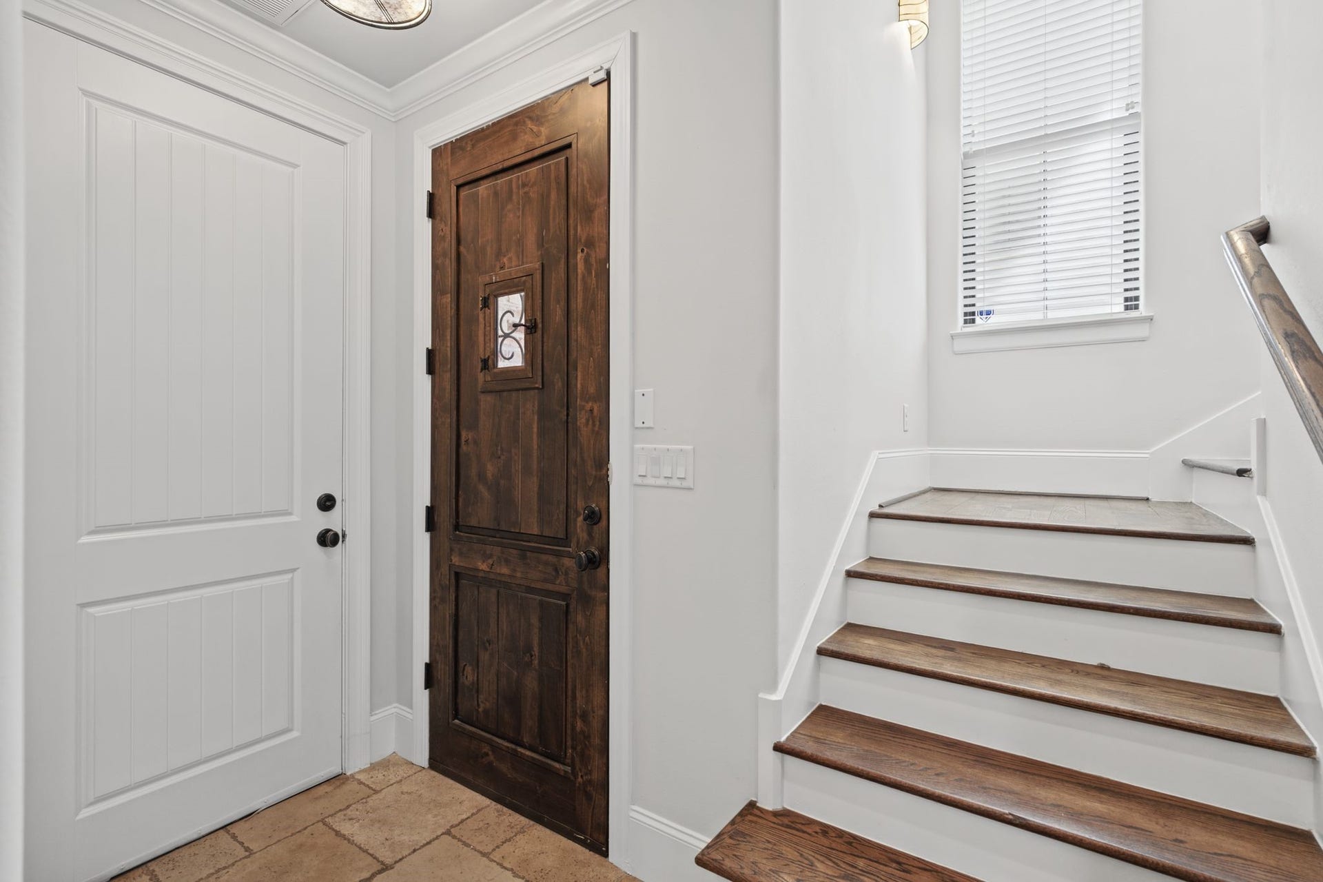 Entry [9 x 13]  First Floor. A welcoming introduction to the homes Mediterranean character, this light-filled foyer features expansive windows and a graceful staircase with solid oak treads, decorative tile risers, and wrought-iron detailing.