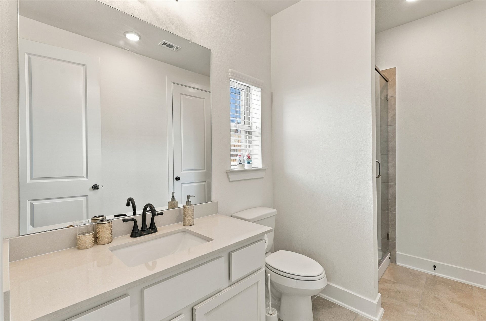 2922 Opal Ivory Way, Richmond, TX 77406 Bright and modern bathroom featuring a sleek vanity with a black faucet, large mirror, and a spacious walk-in shower for a touch of luxury.