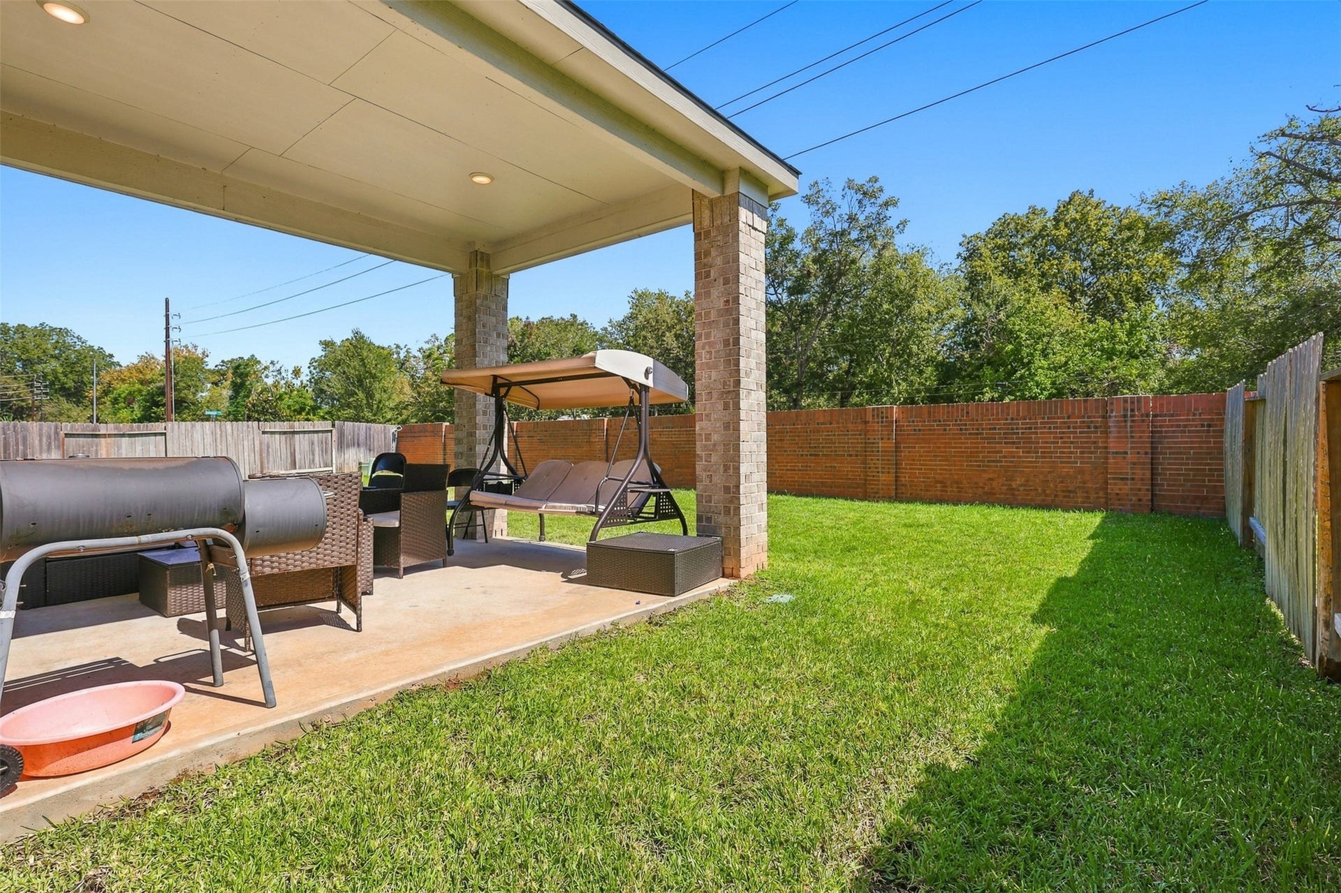 2922 Opal Ivory Way, Richmond, TX 77406 Charming backyard with a covered patio, perfect for relaxation and outdoor entertaining, featuring a cozy swing and ample green space.