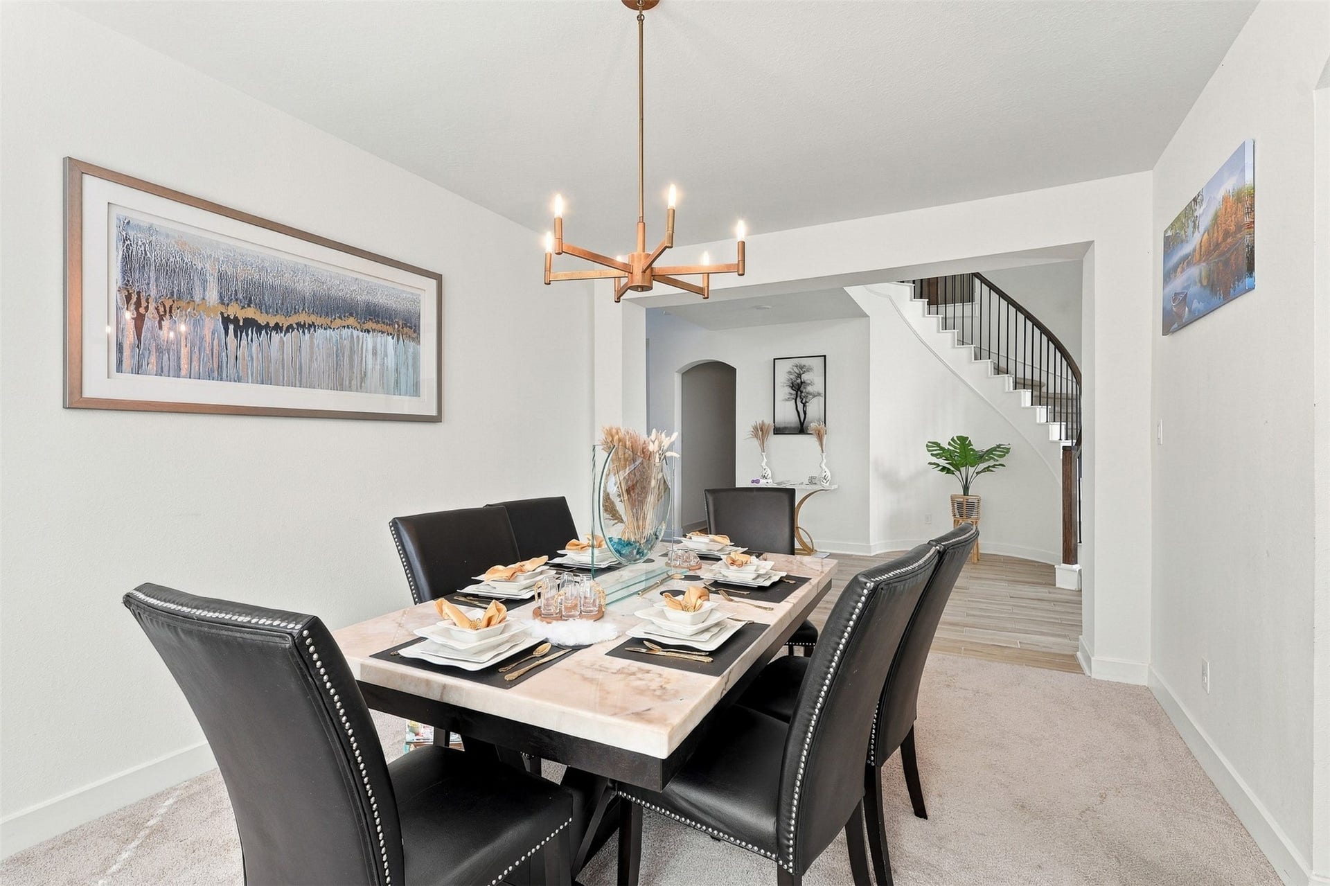 2922 Opal Ivory Way, Richmond, TX 77406 Elegant dining room with a modern chandelier, stylish black chairs, and a chic marble table setting, leading to a graceful staircase.