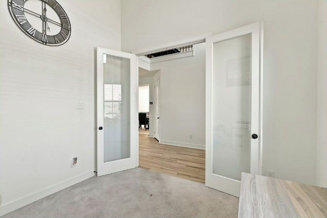 2922 Opal Ivory Way, Richmond, TX 77406 Elegant room with stylish glass French doors and a sleek wall clock, offering a bright and open atmosphere.