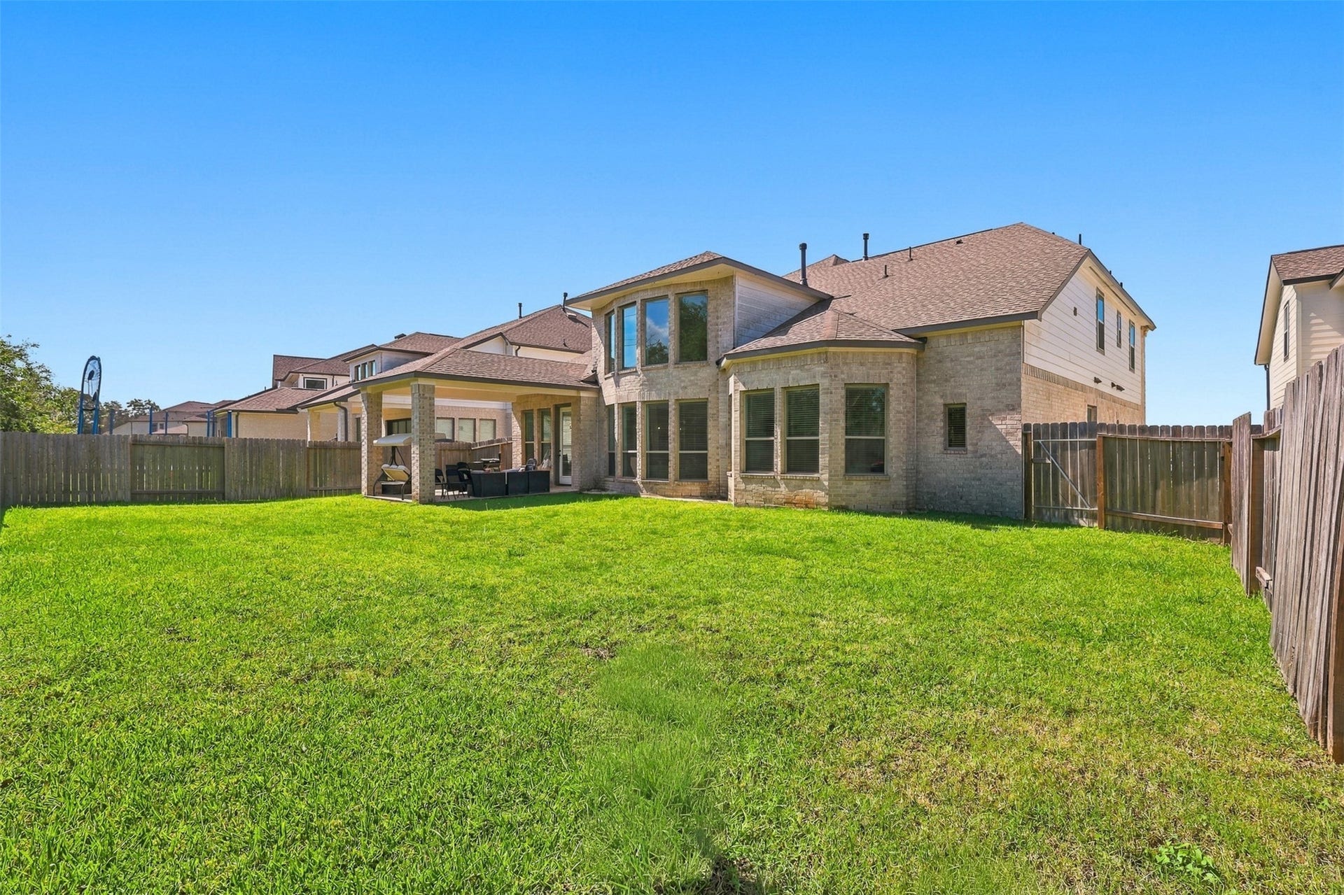 2922 Opal Ivory Way, Richmond, TX 77406 Spacious backyard with a covered patio, perfect for outdoor entertaining, set against a modern two-story home with large windows and a fenced perimeter for privacy.