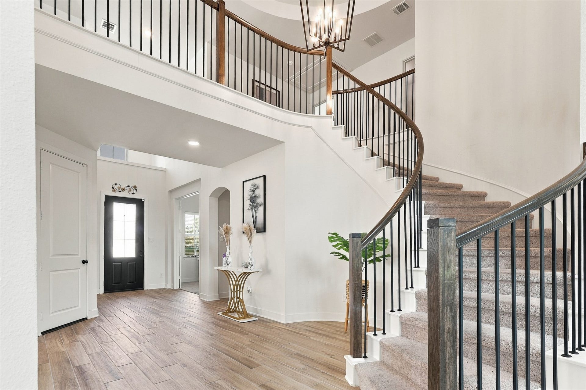 2922 Opal Ivory Way, Richmond, TX 77406 Elegant entryway with a stunning curved staircase, modern chandelier, and stylish wood-look flooring.