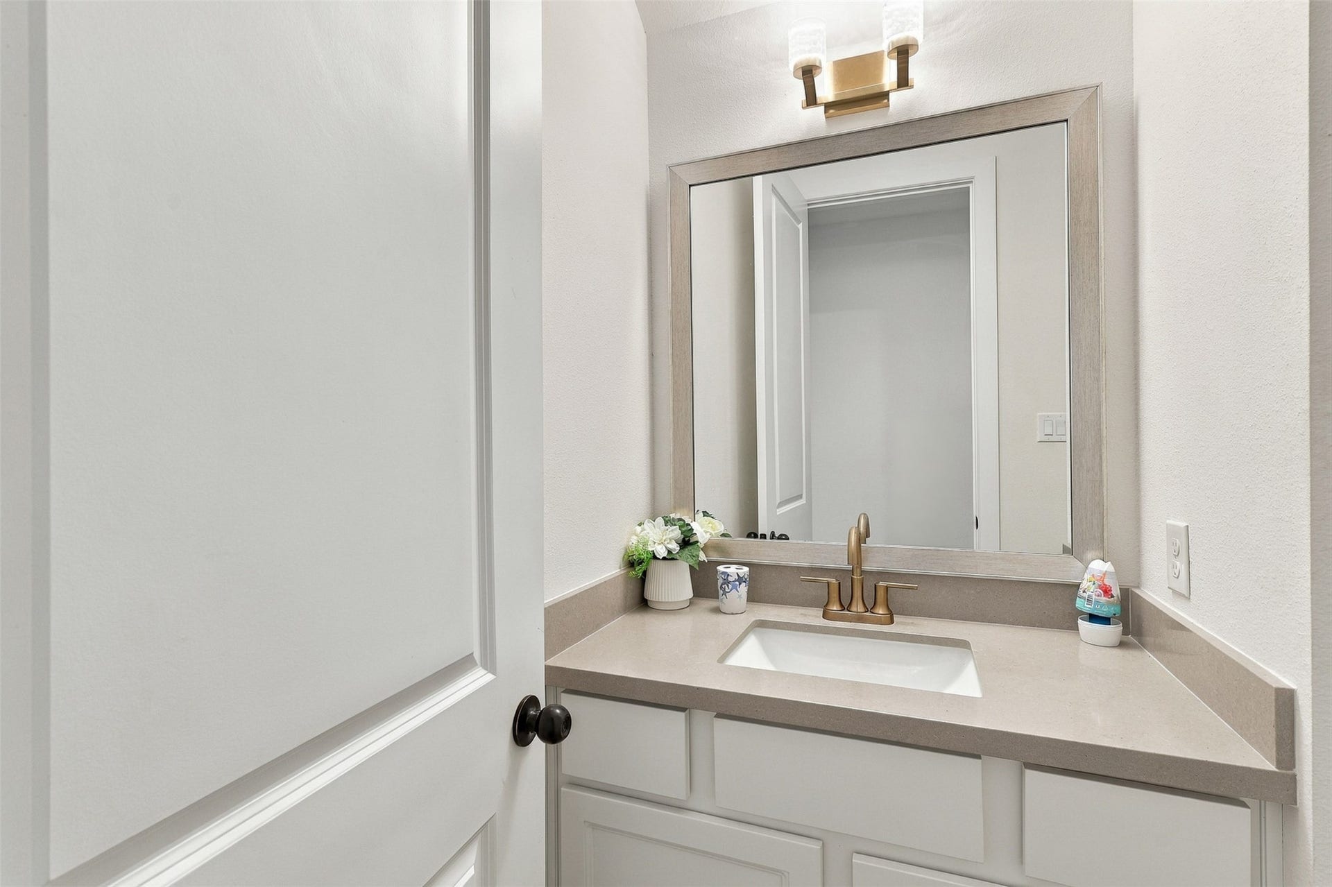 2922 Opal Ivory Way, Richmond, TX 77406 Elegant powder room featuring a sleek vanity with a modern brass faucet, framed mirror, and soft lighting, creating a sophisticated and welcoming ambiance.