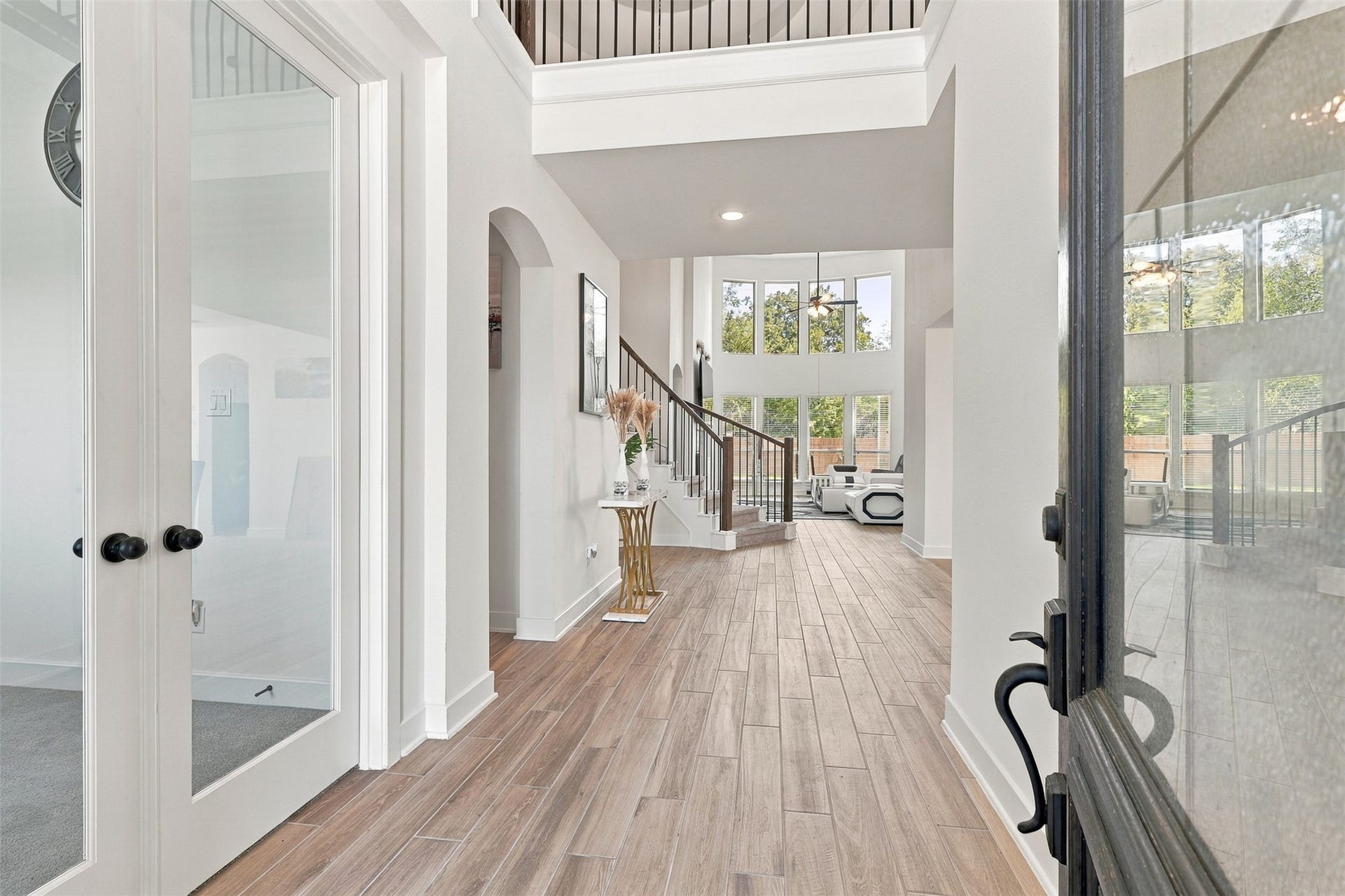 2922 Opal Ivory Way, Richmond, TX 77406 Elegant entryway featuring high ceilings, sleek wood flooring, and a stunning staircase leading to a bright living area with large windows.