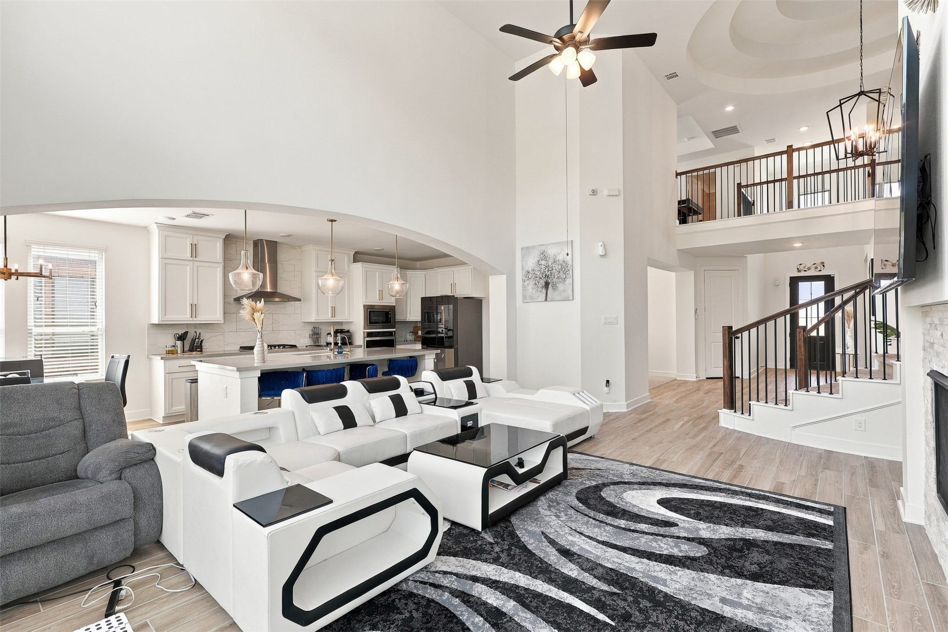 2922 Opal Ivory Way, Richmond, TX 77406 Spacious open-concept living area with high ceilings, featuring a modern kitchen with sleek white cabinetry and stainless steel appliances, an elegant staircase, and a cozy seating area perfect for entertaining.