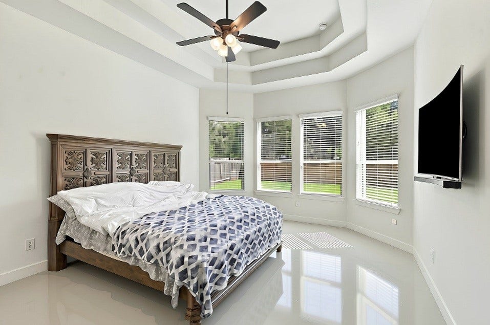 2922 Opal Ivory Way, Richmond, TX 77406 Bright and inviting bedroom with large windows, a stylish tray ceiling, and a cozy wooden bed frame, perfect for relaxation.