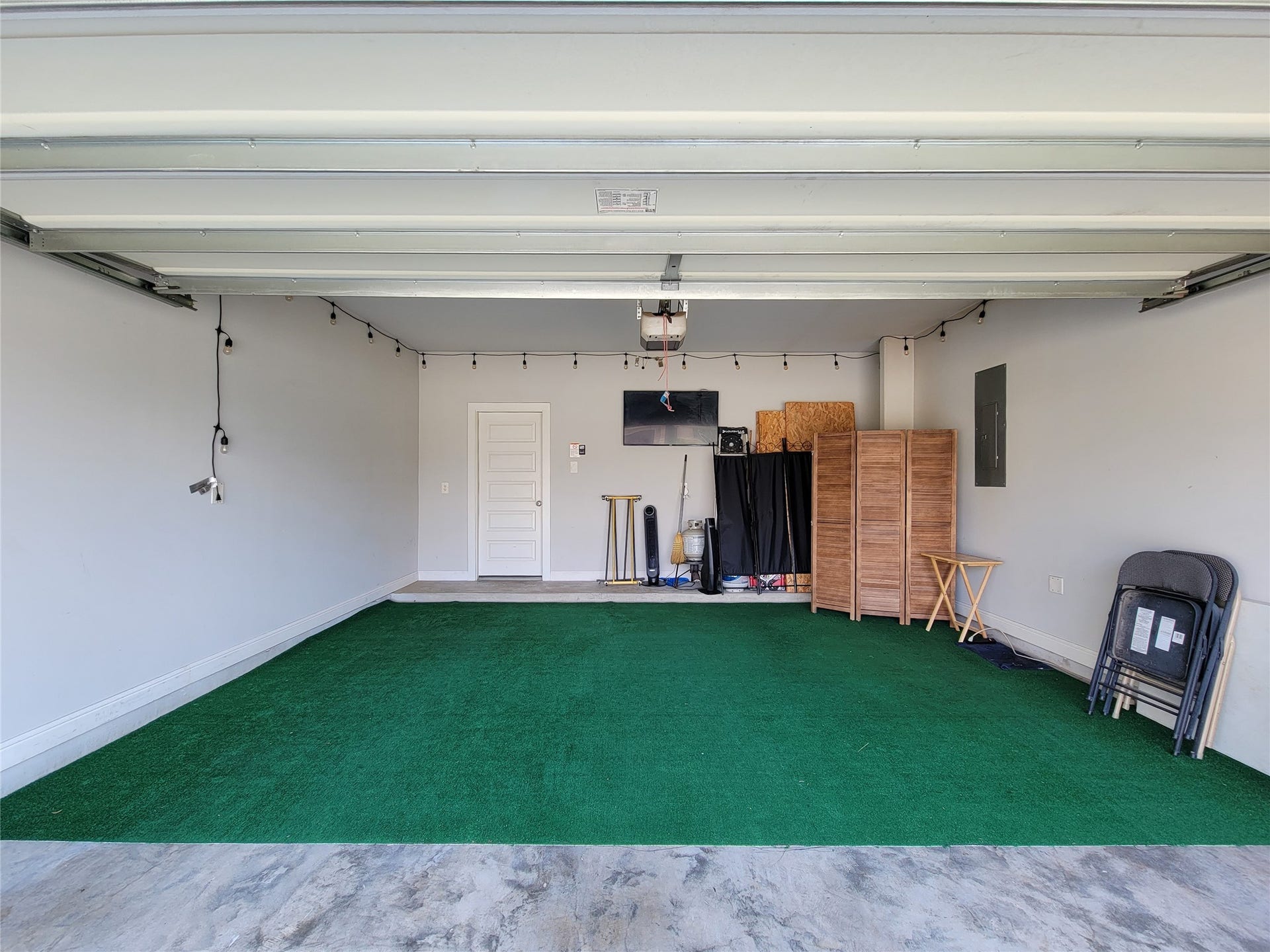 10843 Bodie Hills Drive, Rosharon, TX 77583 Spacious garage with artificial turf flooring, offering ample storage and versatile space for projects or hobbies.