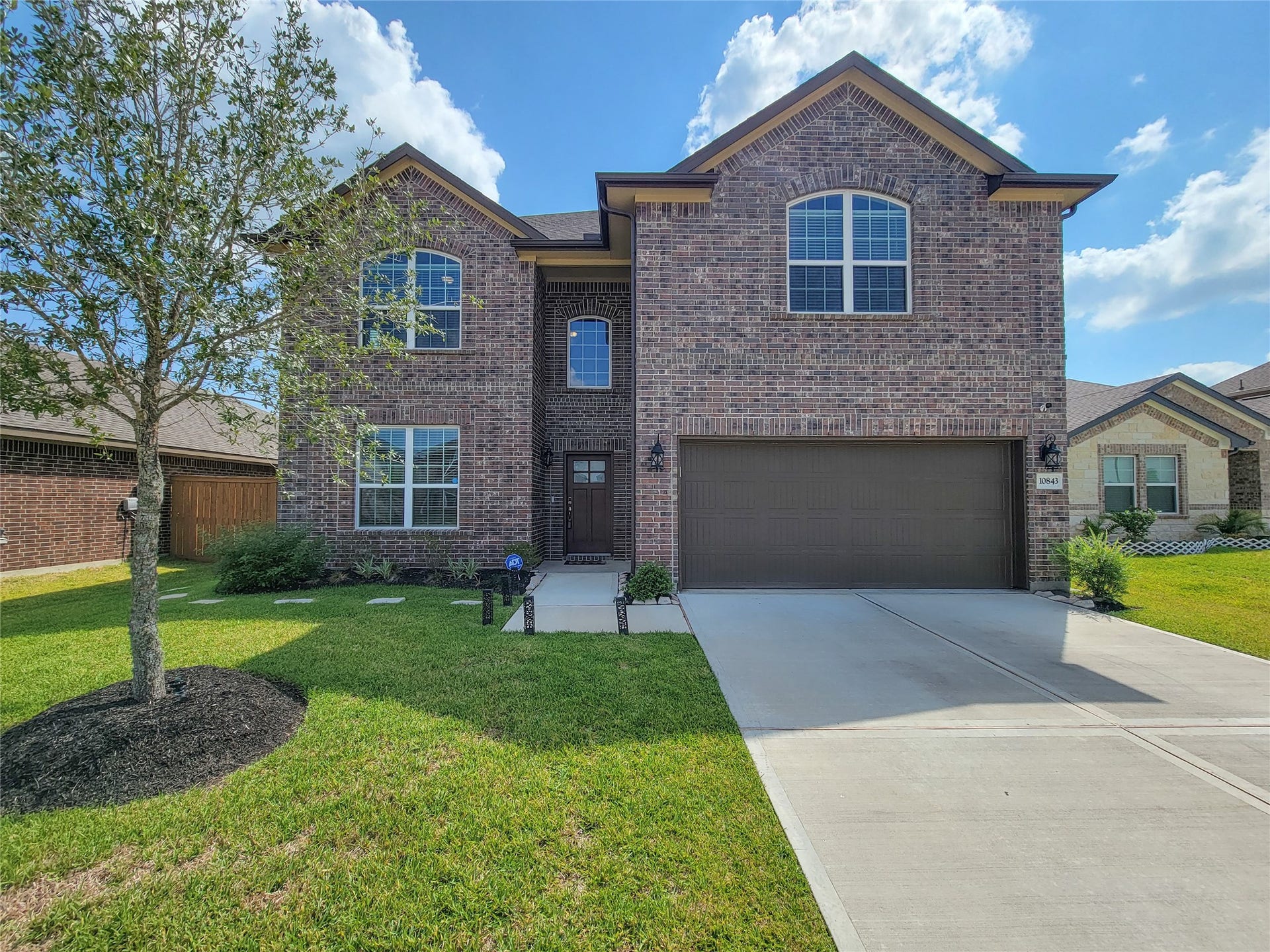 10843 Bodie Hills Drive, Rosharon, TX 77583 Stunning two-story brick home with a spacious driveway and attached garage, complemented by a well-maintained front lawn and charming landscaping.
