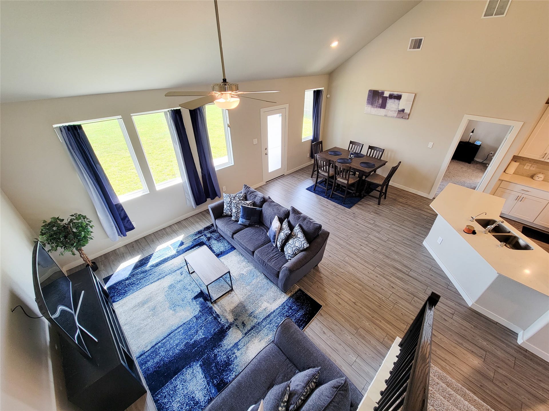 10843 Bodie Hills Drive, Rosharon, TX 77583 Bright and airy open-concept living space features high ceilings, stylish wood flooring, and large windows that flood the room with natural light. The modern kitchen with a breakfast bar seamlessly connects to the cozy living area, perfect for entertaining.