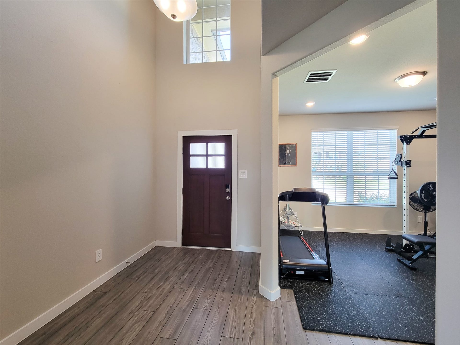 10843 Bodie Hills Drive, Rosharon, TX 77583 Inviting entryway with high ceilings and elegant flooring, leading to a bright home gym filled with natural light.
