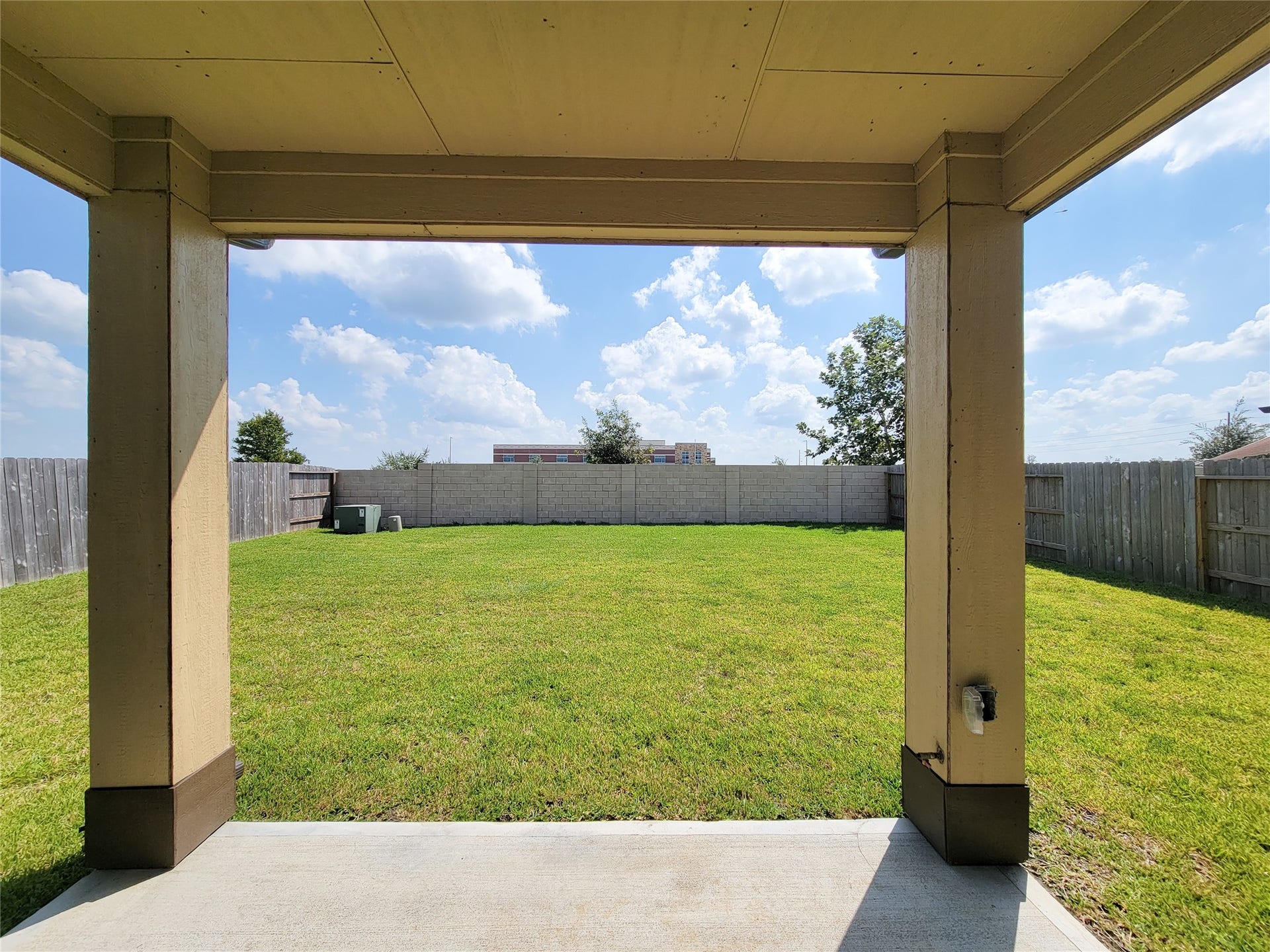 10843 Bodie Hills Drive, Rosharon, TX 77583 Expansive backyard with lush green lawn, perfect for outdoor activities and relaxation, framed by a covered patio offering a shaded retreat.
