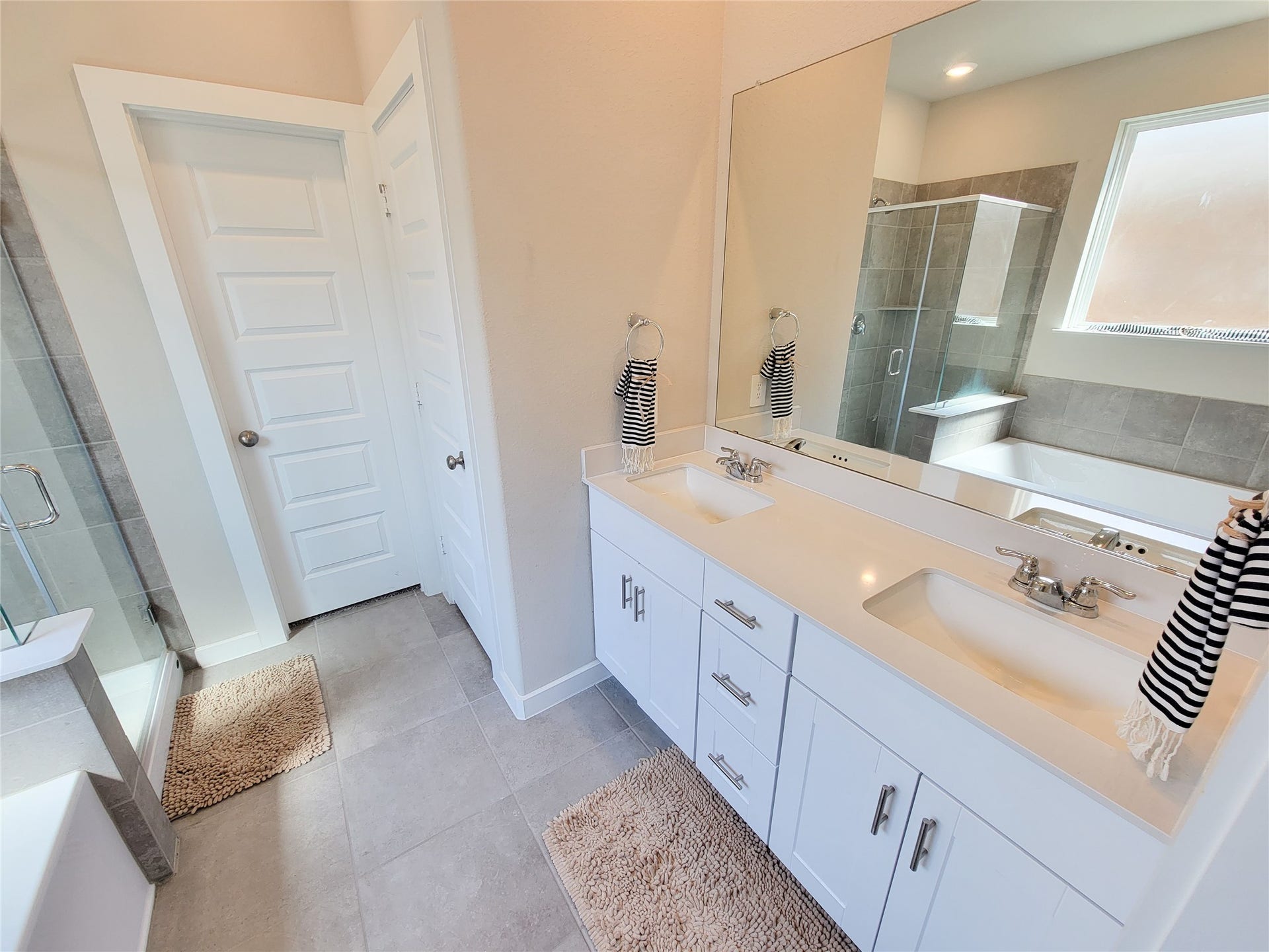 10843 Bodie Hills Drive, Rosharon, TX 77583 Elegant bathroom featuring a spacious double vanity with sleek fixtures, a large mirror, and a separate glass-enclosed shower.