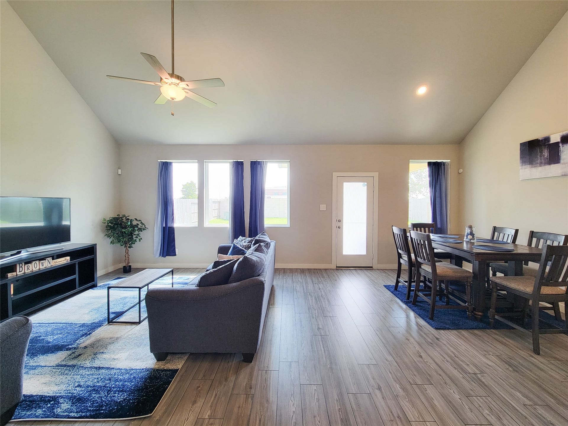10843 Bodie Hills Drive, Rosharon, TX 77583 Spacious living and dining area with vaulted ceilings, abundant natural light, and elegant wood flooring, creating a warm and inviting atmosphere.