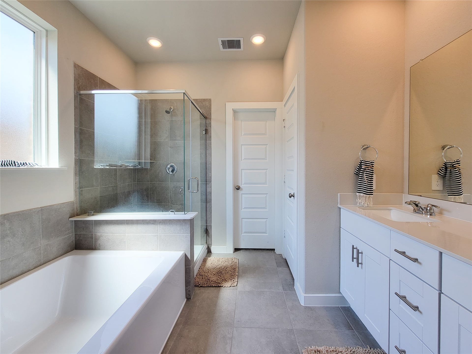10843 Bodie Hills Drive, Rosharon, TX 77583 Elegant bathroom featuring a spacious glass-enclosed shower, a sleek bathtub, and a modern vanity with ample storage and a large mirror.