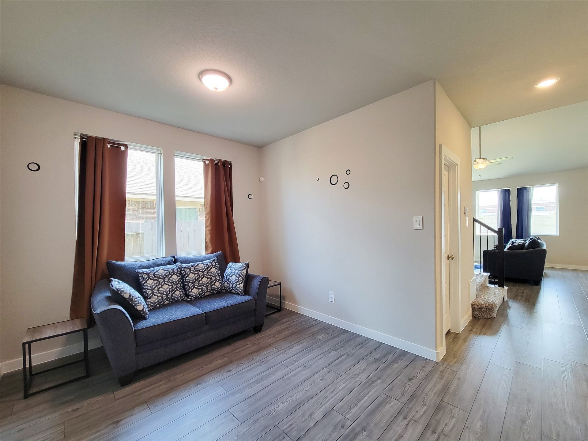 10843 Bodie Hills Drive, Rosharon, TX 77583 Bright and inviting living space featuring sleek hardwood floors, modern lighting, and ample natural light through large windows, perfect for relaxation and entertaining.