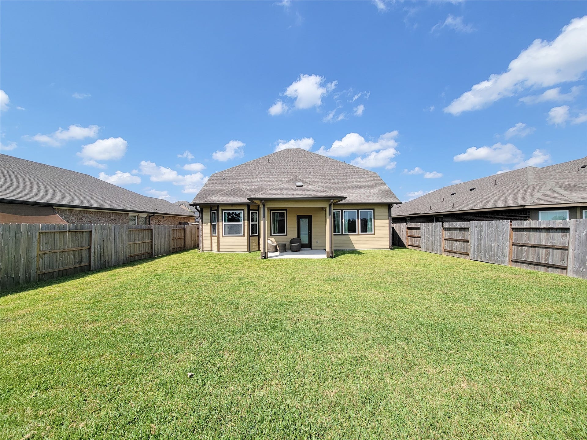 10843 Bodie Hills Drive, Rosharon, TX 77583 Spacious and inviting backyard with a well-maintained lawn, privacy fencing, and a charming covered patio perfect for outdoor gatherings.