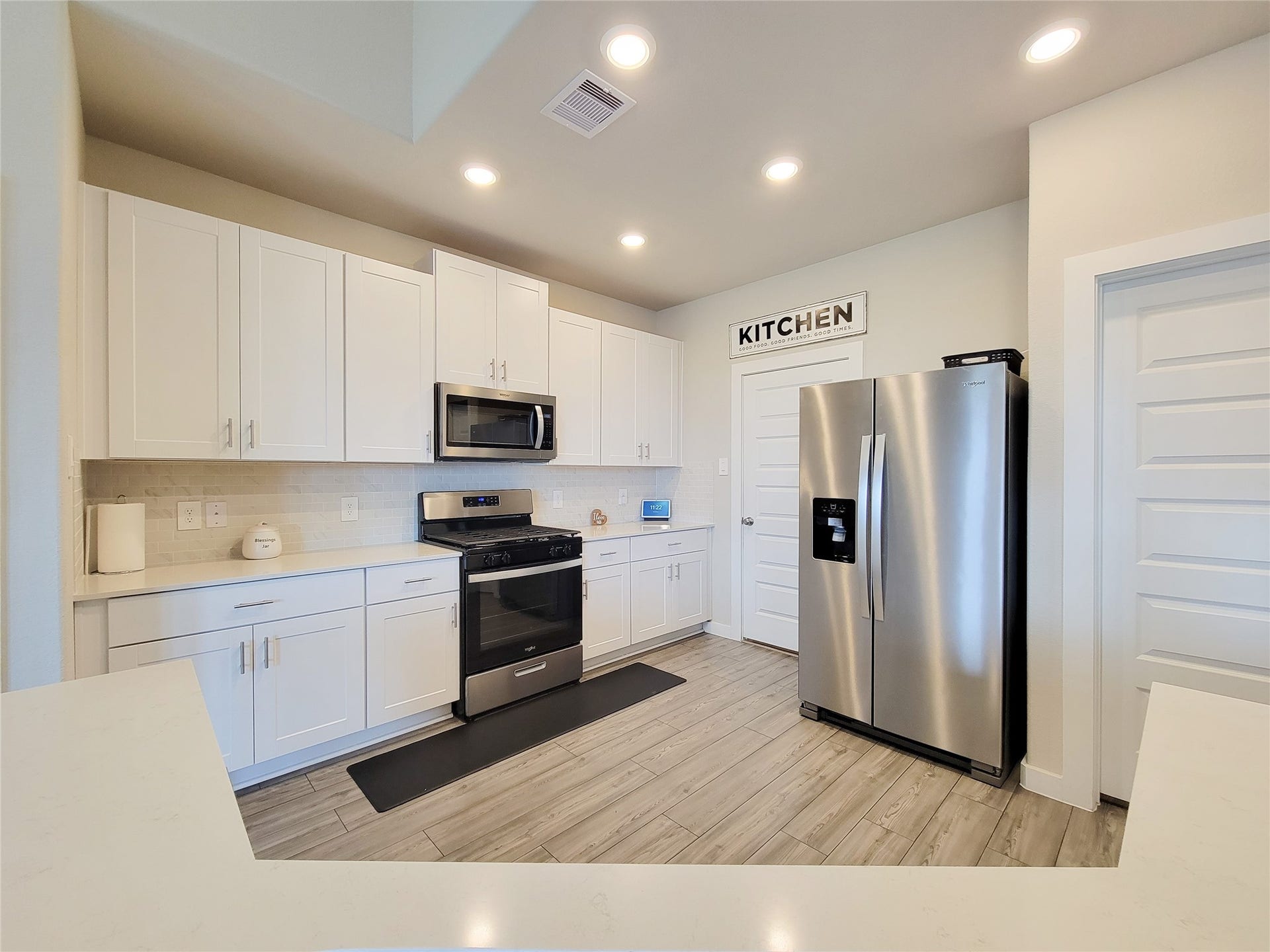 10843 Bodie Hills Drive, Rosharon, TX 77583 Modern kitchen with sleek stainless steel appliances, crisp white cabinetry, and stylish wood-look flooring, offering a bright and functional space for cooking and entertaining.