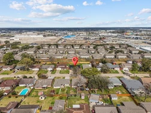 11007 Green Arbor Drive, Houston, TX 77089 This aerial photo showcases a residential neighborhood with neatly arranged houses and spacious yards. A red marker highlights a specific property. The area appears well-maintained, with some homes featuring pools. In the background, there are commercial and industrial buildings, indicating proximity to urban amenities.