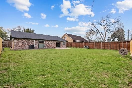 11007 Green Arbor Drive, Houston, TX 77089 This photo shows a spacious backyard with a well-maintained lawn, bordered by a new wooden fence. The house has a brick exterior and large windows, offering a cozy and private outdoor space ideal for family activities or entertaining.
