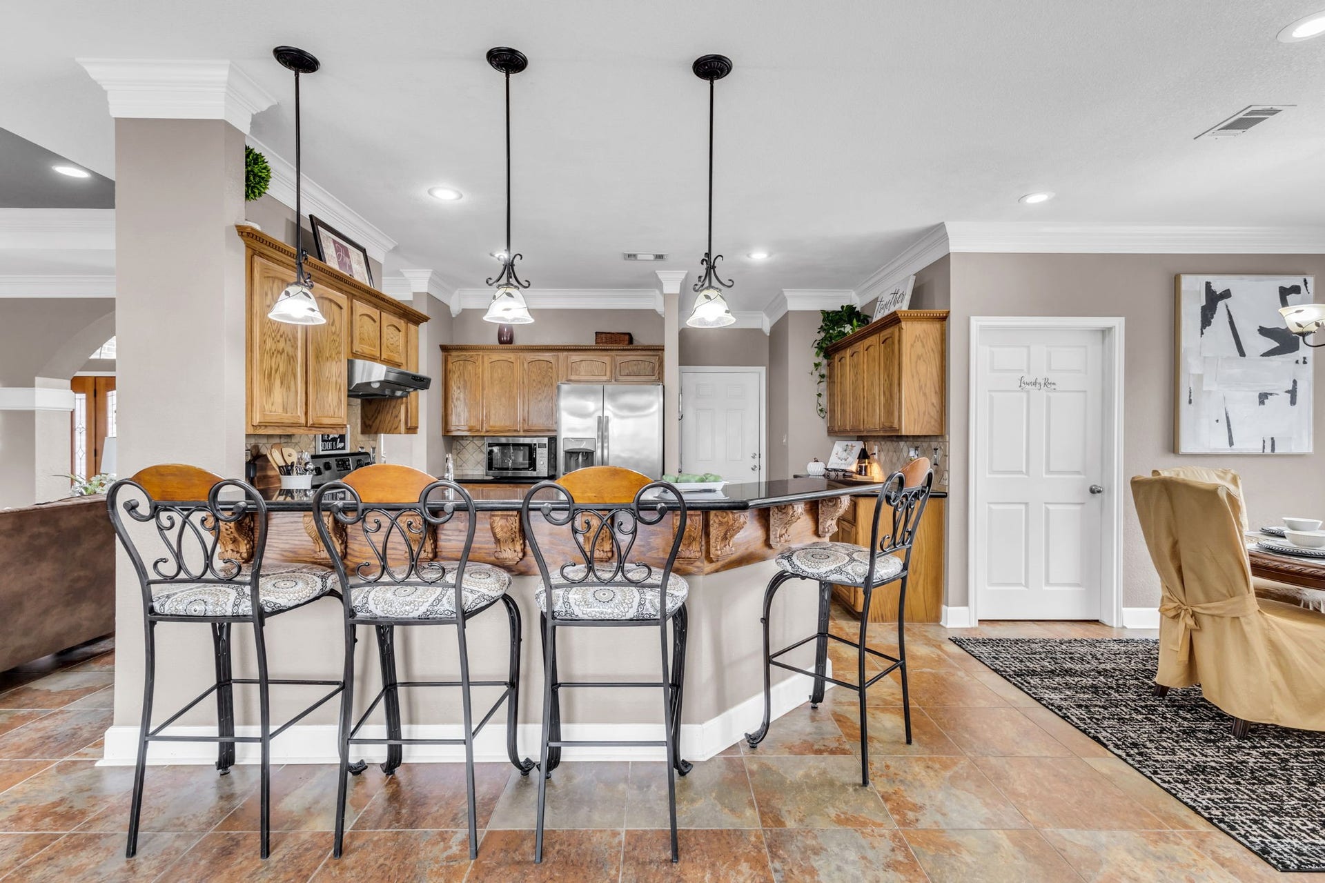 11010 Madison Court, Beaumont, TX 77705 Spacious kitchen featuring a large breakfast bar, abundant wood cabinetry, and decorative pendant lighting. The open design connects seamlessly to the living and dining areas, ideal for everyday living and entertaining.