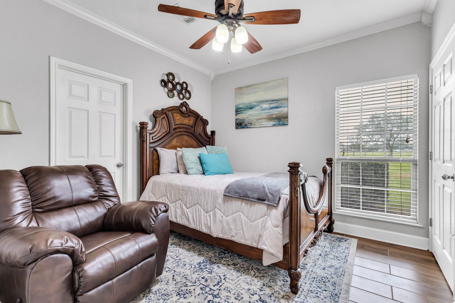 11010 Madison Court, Beaumont, TX 77705 Another view of guest bedroom one, featuring wood-look flooring, crown molding, a ceiling fan, and a large window that brings in natural light. The room offers a comfortable layout with ample closet space.