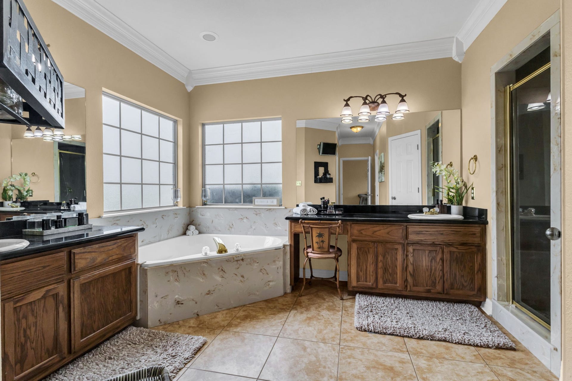 11010 Madison Court, Beaumont, TX 77705 Spacious primary bathroom featuring separate vanities, a relaxing soaking tub surrounded by windows, a separate glass-enclosed shower, and plenty of cabinet space. A comfortable and functional layout for everyday convenience.